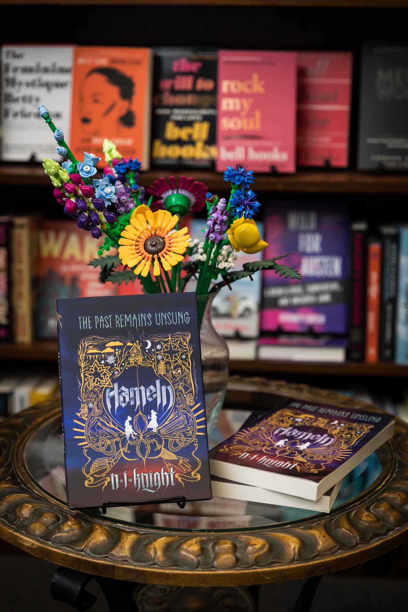 Two copies of Hameln book on table in front of bookshelf with lego flower bouquet in background at an Austin book launch party