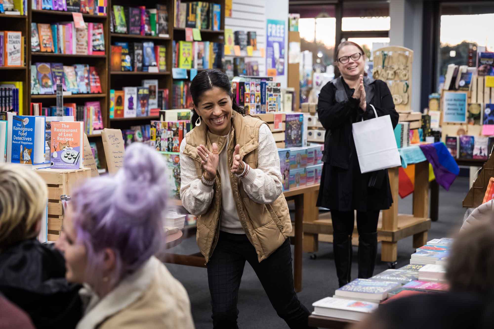 Austin book launch party photos of two women clapping in front of shelves filled with books