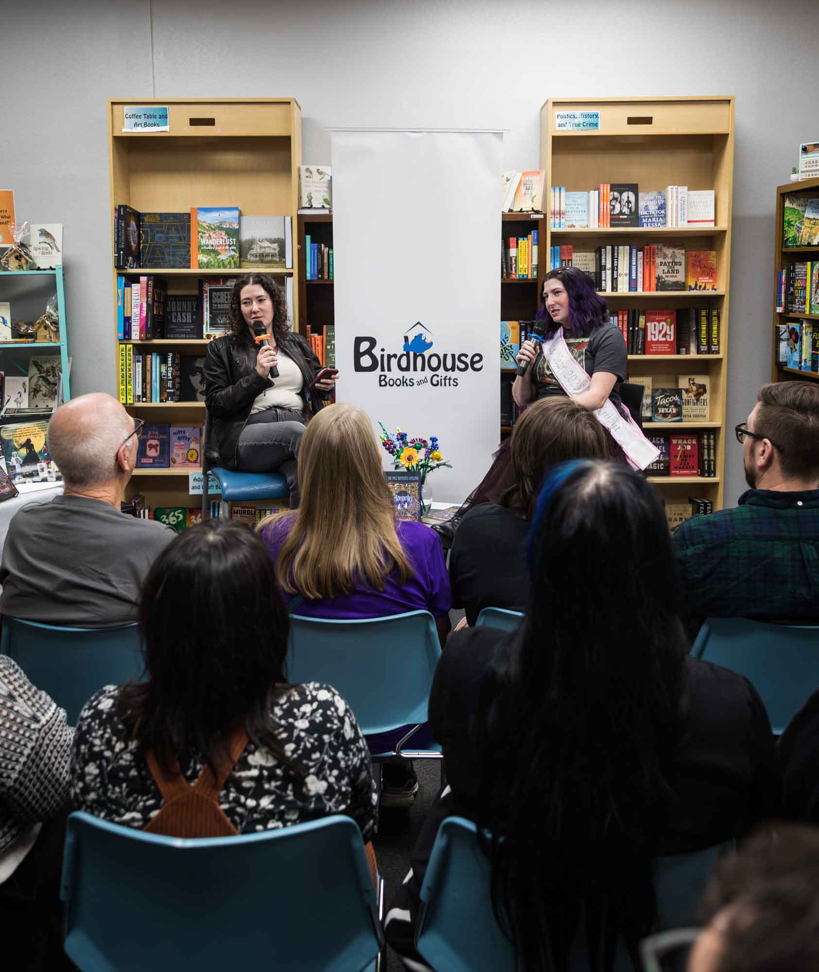Austin book launch party photos of authors Nancy Knight and Erin Cotter speaking into microphone in front of shelves filled with books