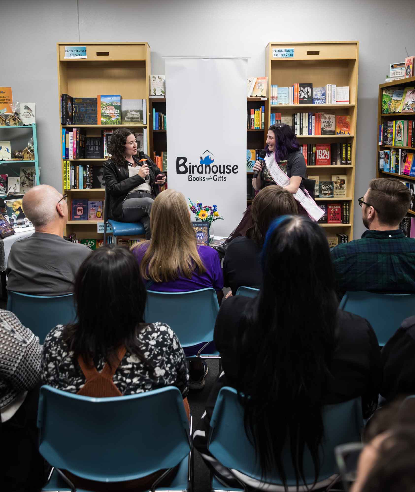 Austin book launch party photos of authors Nancy Knight and Erin Cotter speaking into microphone in front of shelves filled with books