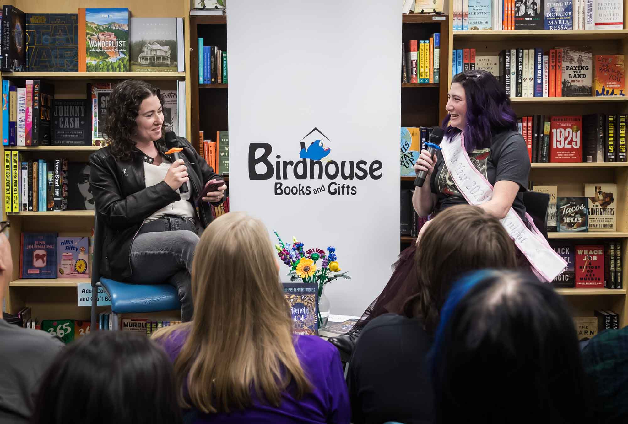 Austin book launch party photos of authors Nancy Knight and Erin Cotter speaking into microphone in front of shelves filled with books
