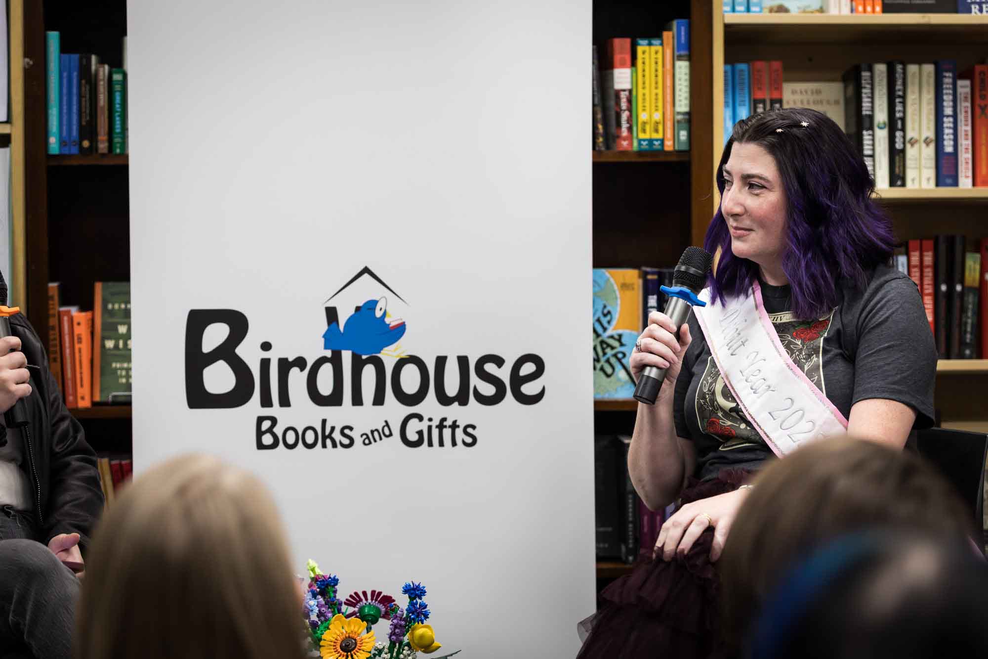 Austin book launch party photos of author Nancy Knight speaking into microphone in front of shelves filled with books