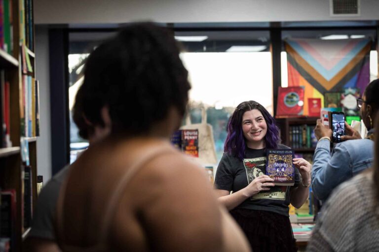 Austin book launch party photos of author Nancy Knight showing book Hameln to guest in middle of bookstore