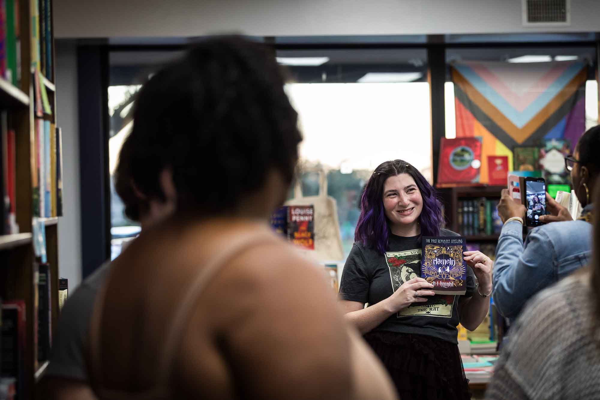 Austin book launch party photos of author Nancy Knight showing book Hameln to guest in middle of bookstore
