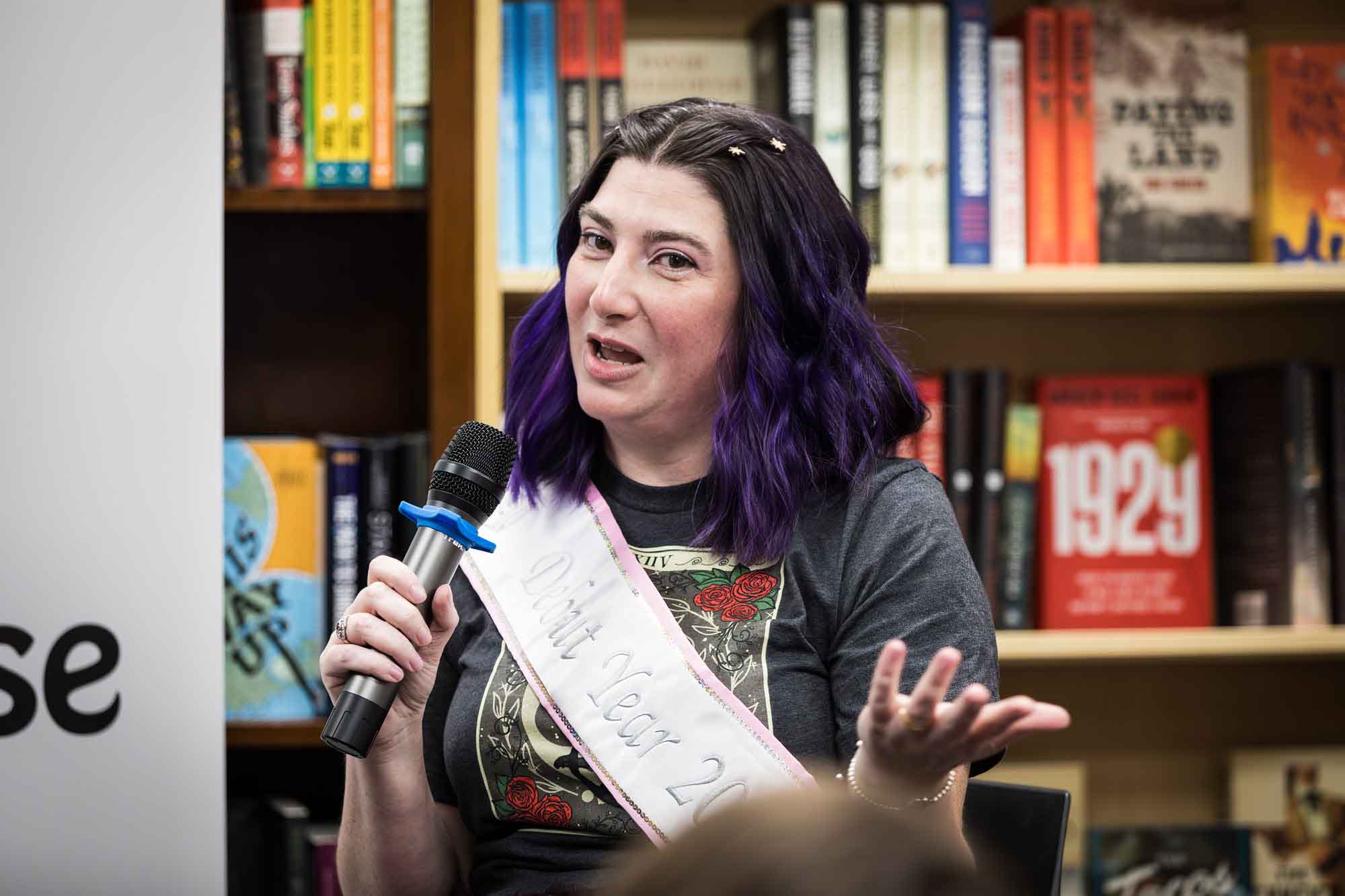 Austin book launch party photos of author Nancy Knight speaking into microphone in front of shelves filled with books