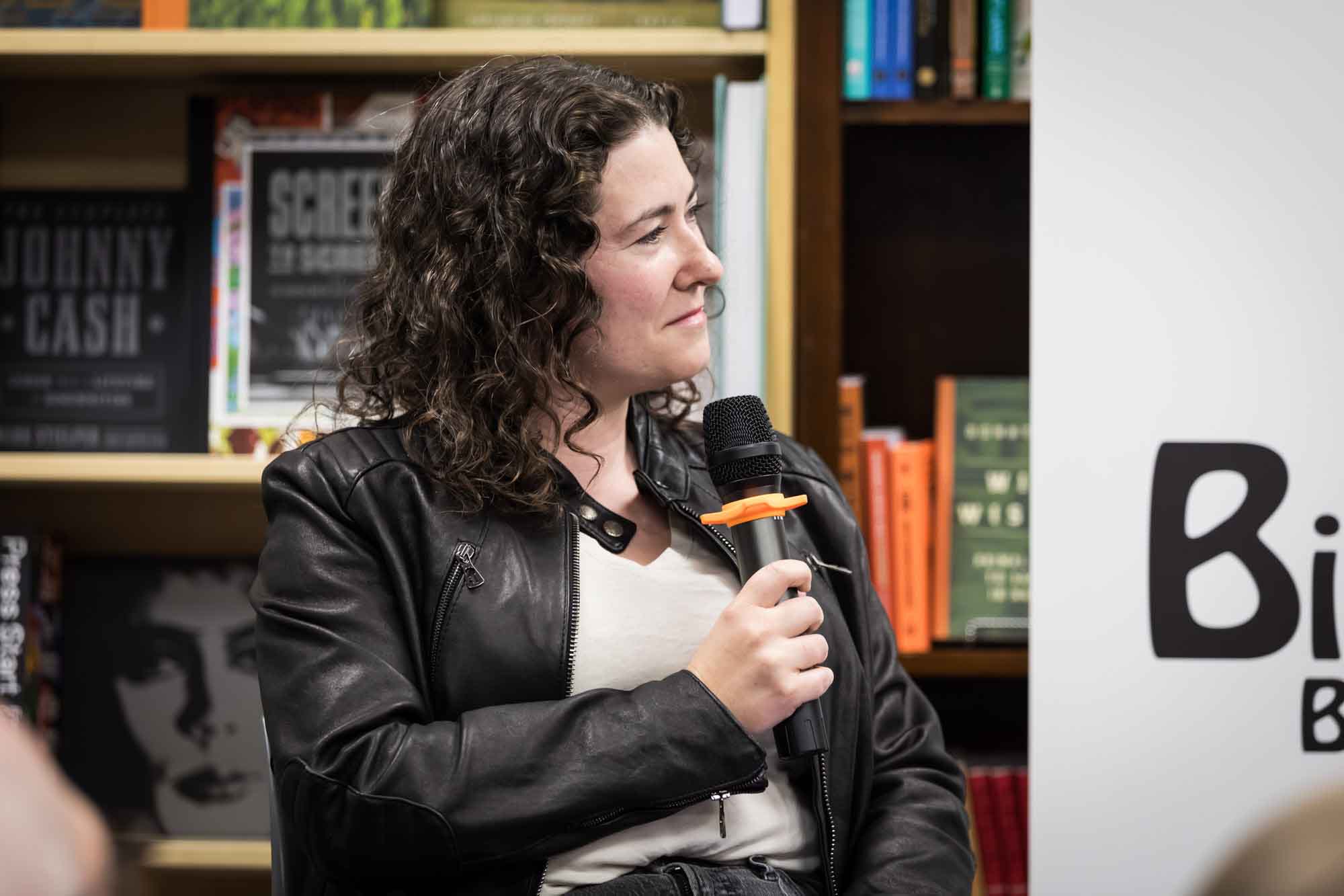 Austin book launch party photos of author Erin Cotter speaking into microphone in front of shelves filled with books