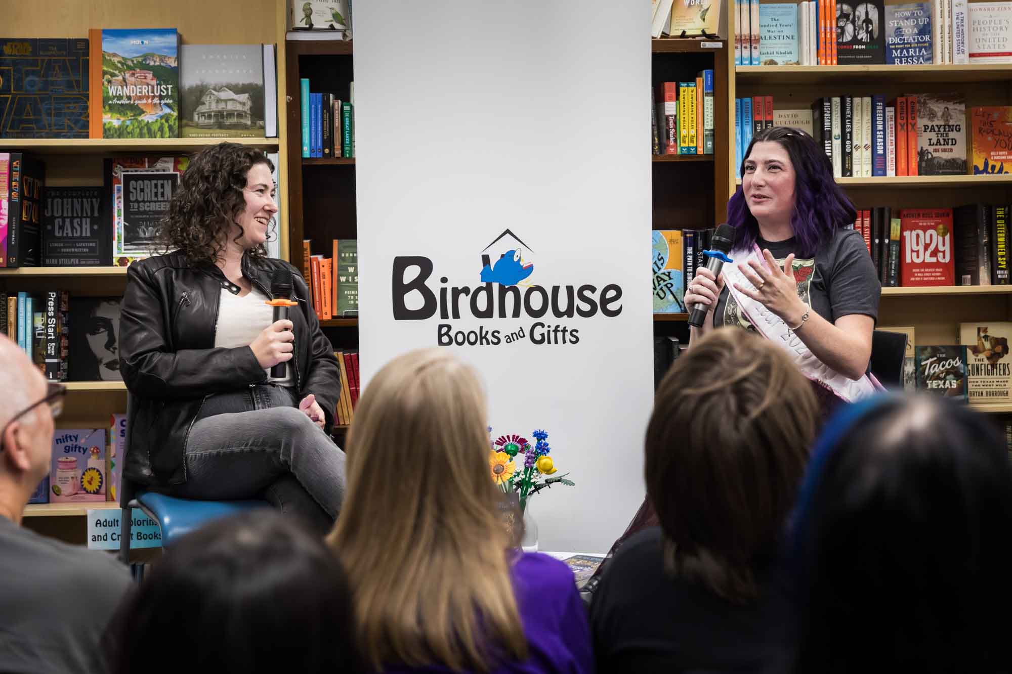 Austin book launch party photos of authors Nancy Knight and Erin Cotter speaking into microphone in front of shelves filled with books