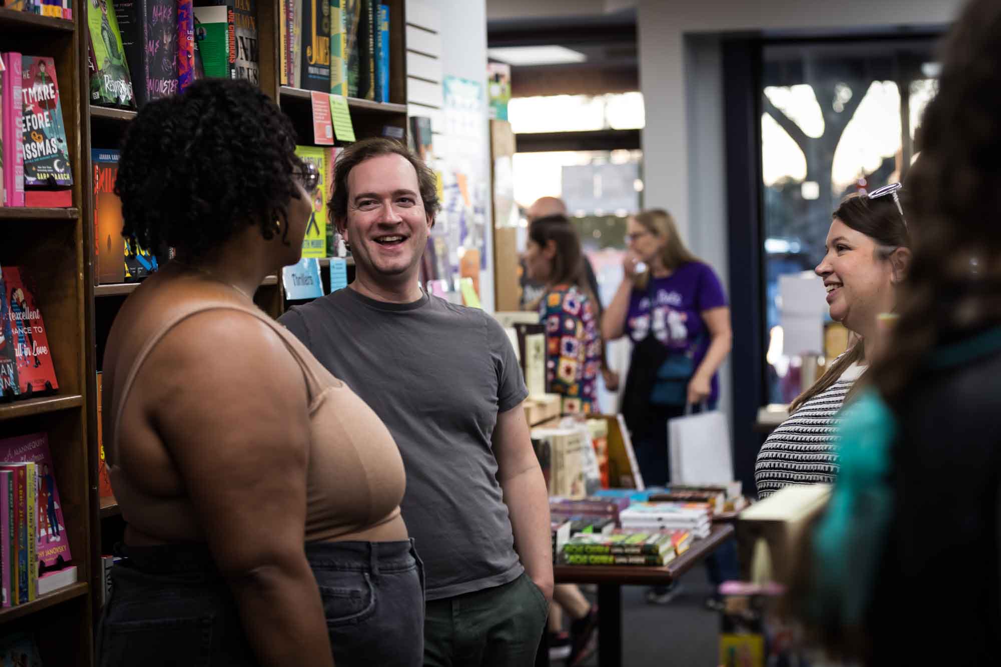 Austin book launch party photos of guests talking in middle of Birdhouse Books surrounded by shelves of books