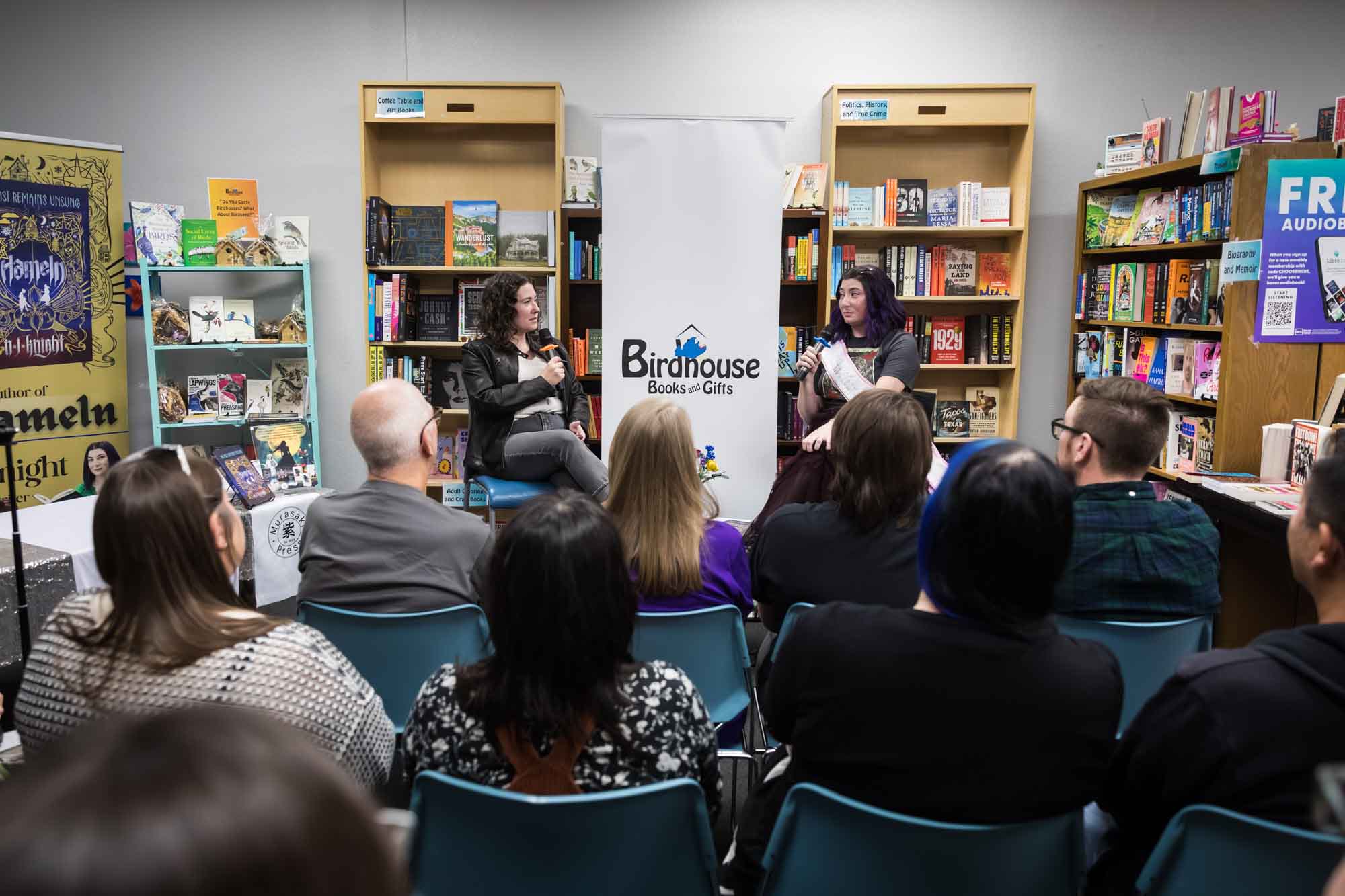 Austin book launch party photos of authors Nancy Knight and Erin Cotter speaking into microphone in front of shelves filled with books
