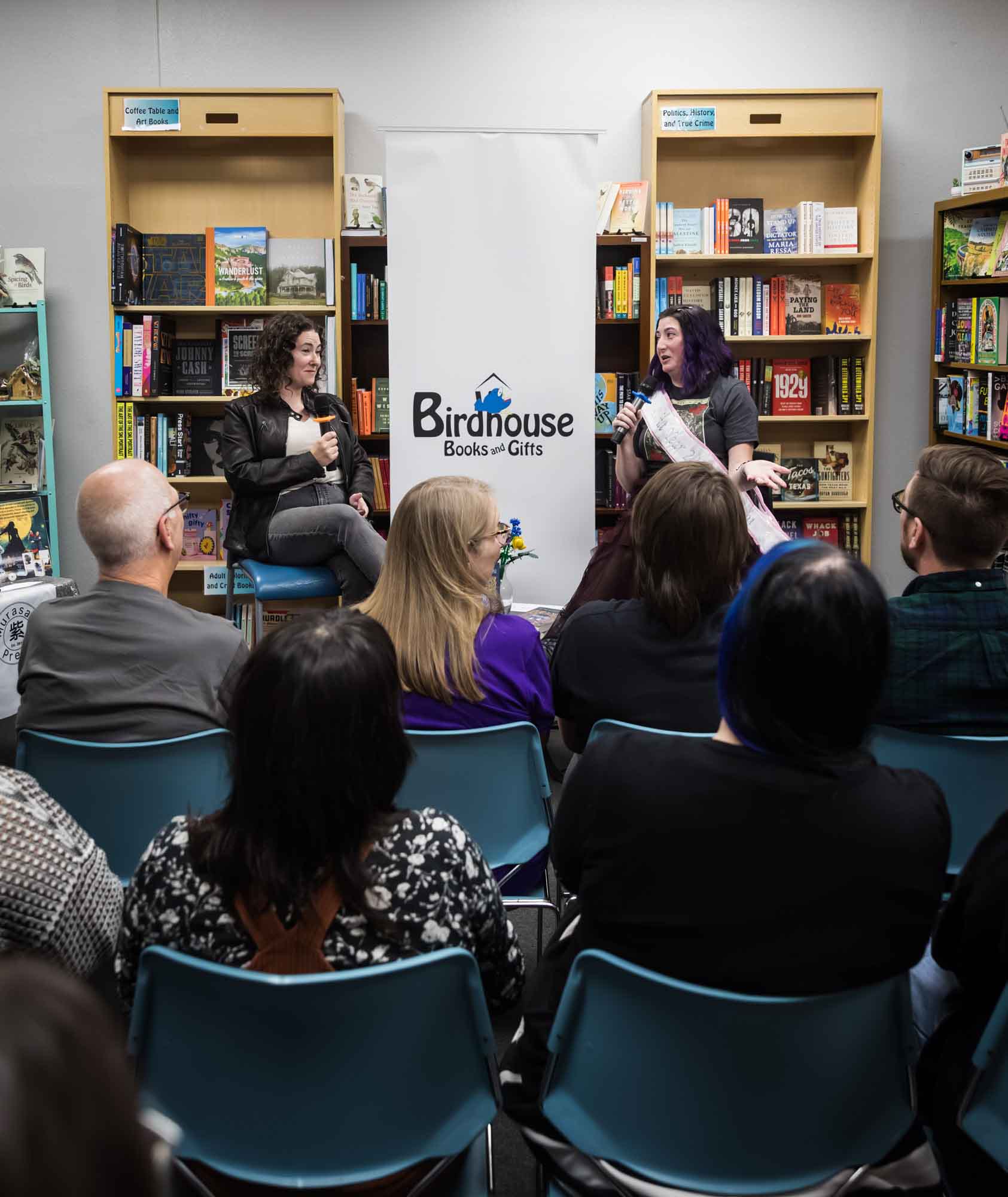 Austin book launch party photos of authors Nancy Knight and Erin Cotter speaking into microphone in front of shelves filled with books
