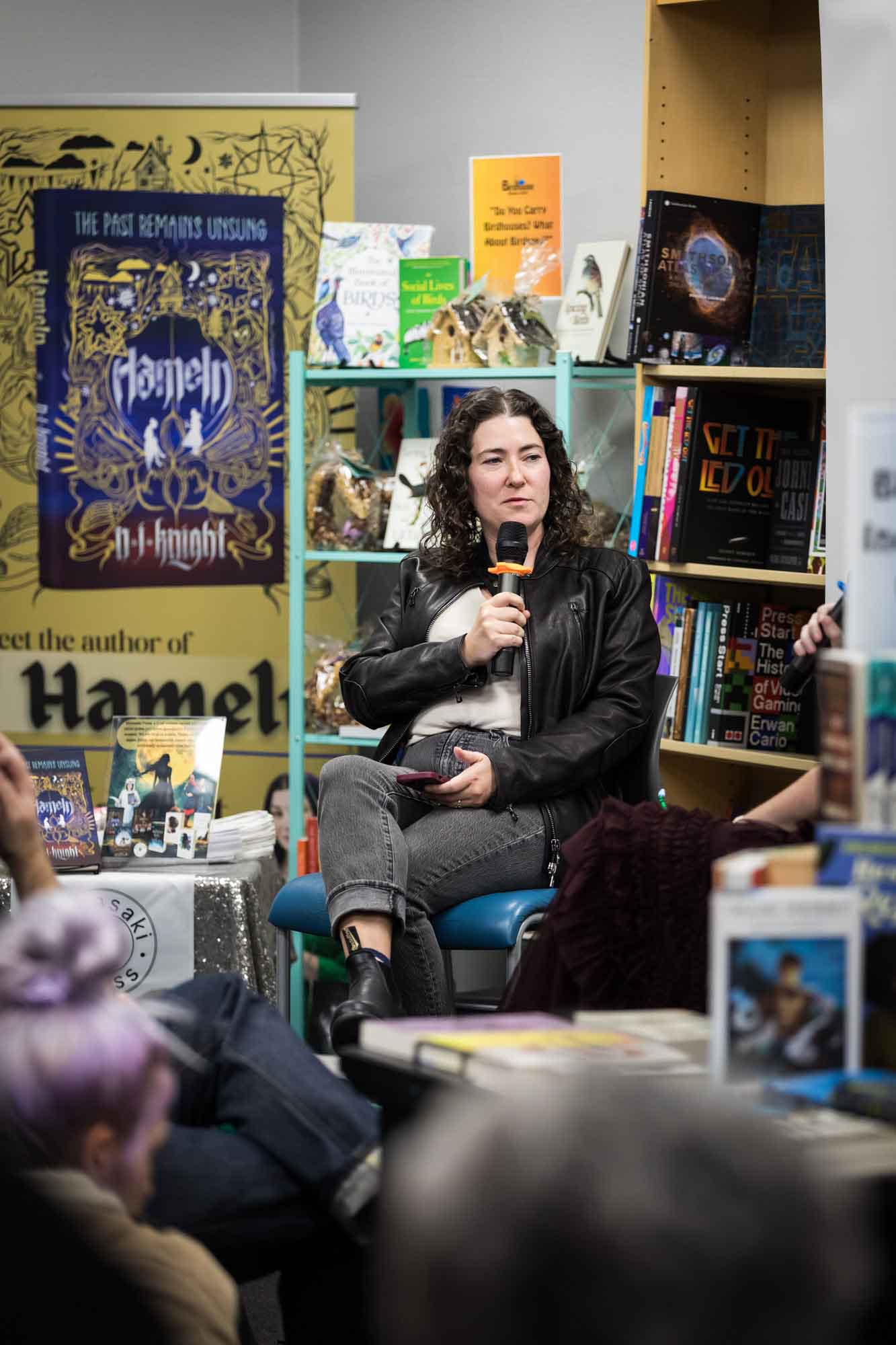 Austin book launch party photos of author Erin Cotter speaking into microphone in front of shelves filled with books