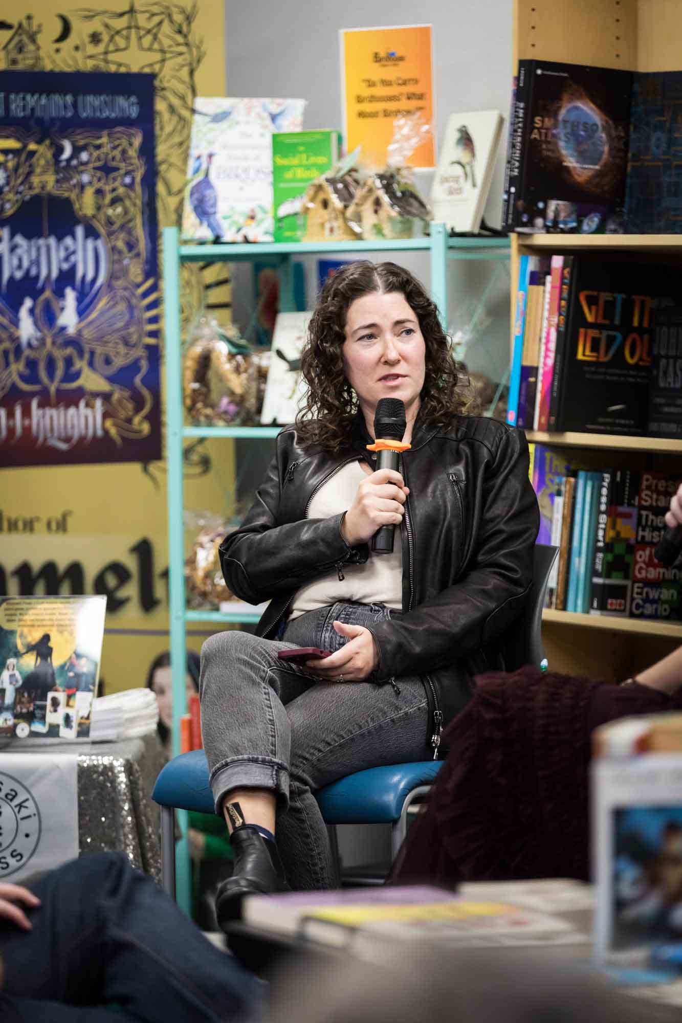 Austin book launch party photos of author Erin Cotter speaking into microphone in front of shelves filled with books