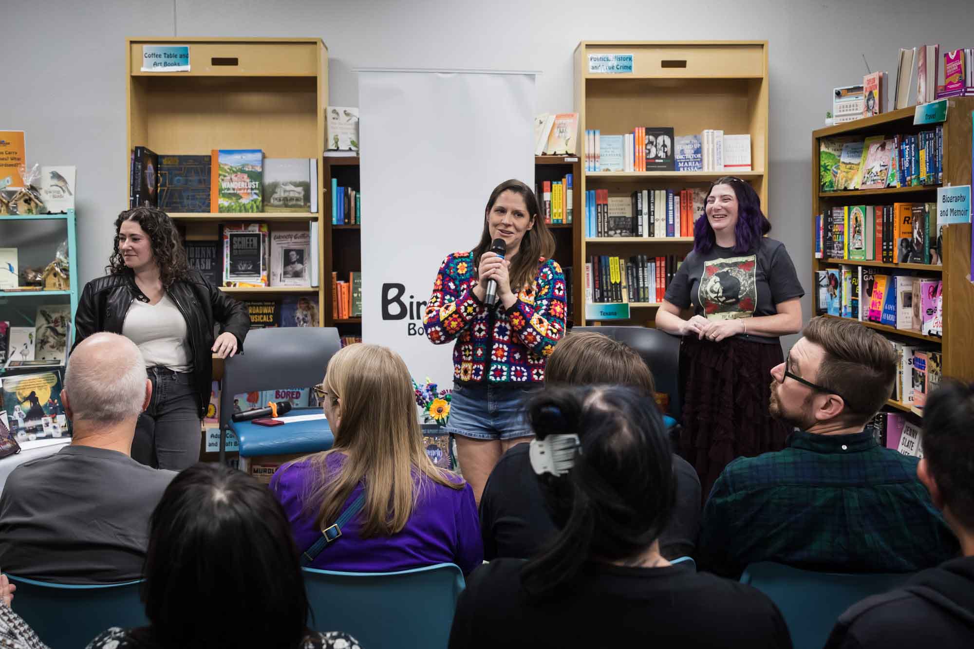 Austin book launch party photos of Birdhouse Books owner Abby talking into microphone in front of authors Erin Cotter and Nancy Knight and guests
