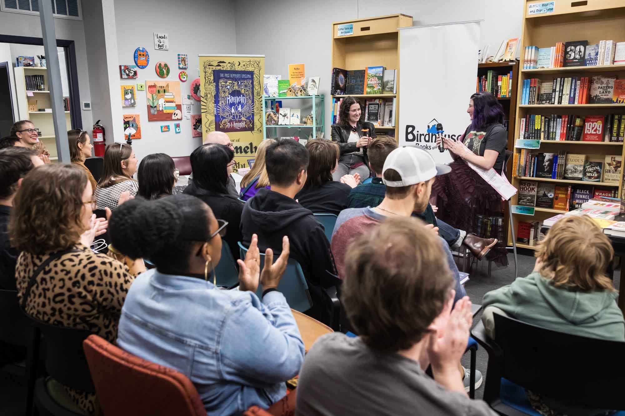 Austin book launch party photos of authors Nancy Knight and Erin Cotter speaking into microphone in front of shelves filled with books