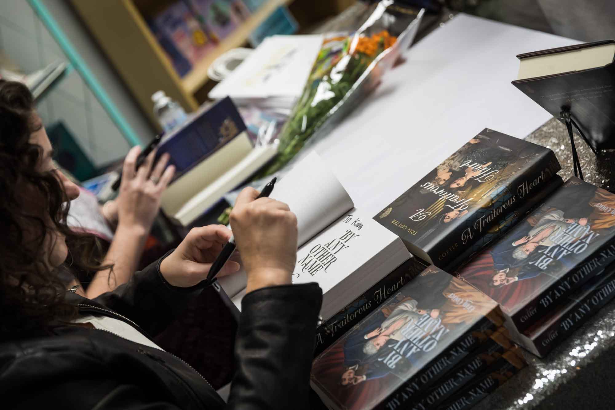 Close up on hands of authors Erin Cotter and Nancy Knight signing books at Birdhouse Books