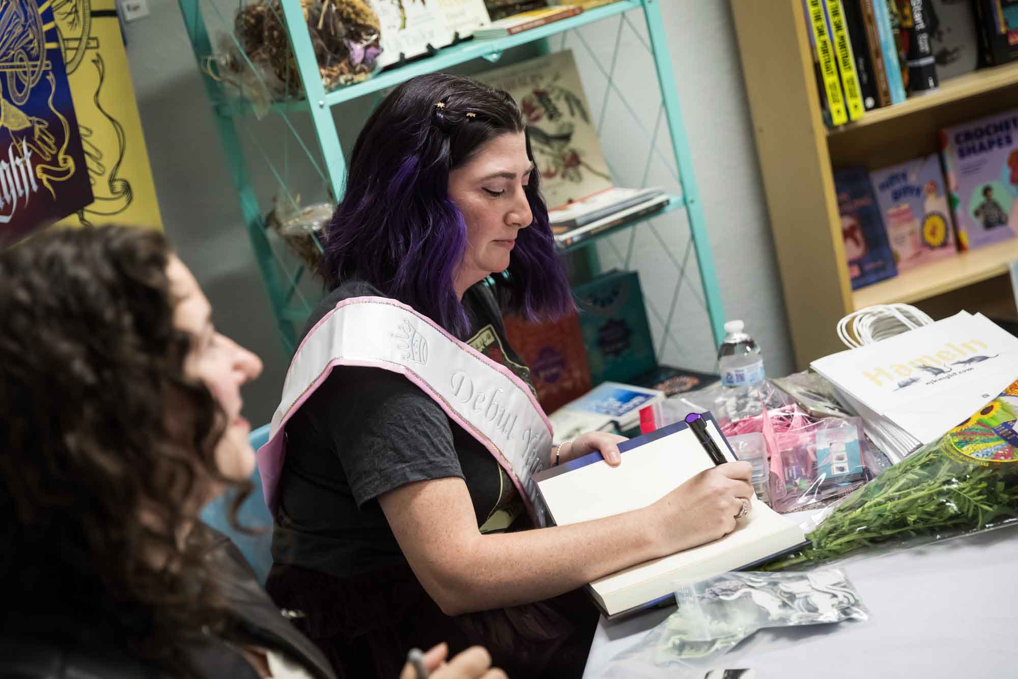 Austin book launch party photos of author Nancy Knight signing book Hameln while seated