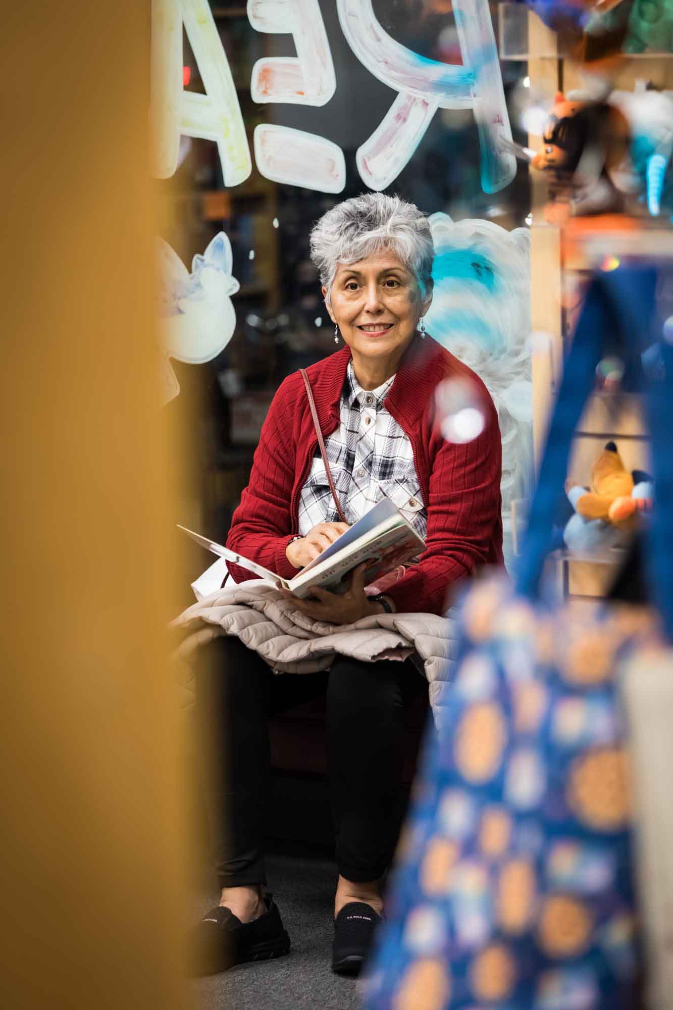 Austin book launch party photos of older woman wearing red sweater seated holding book