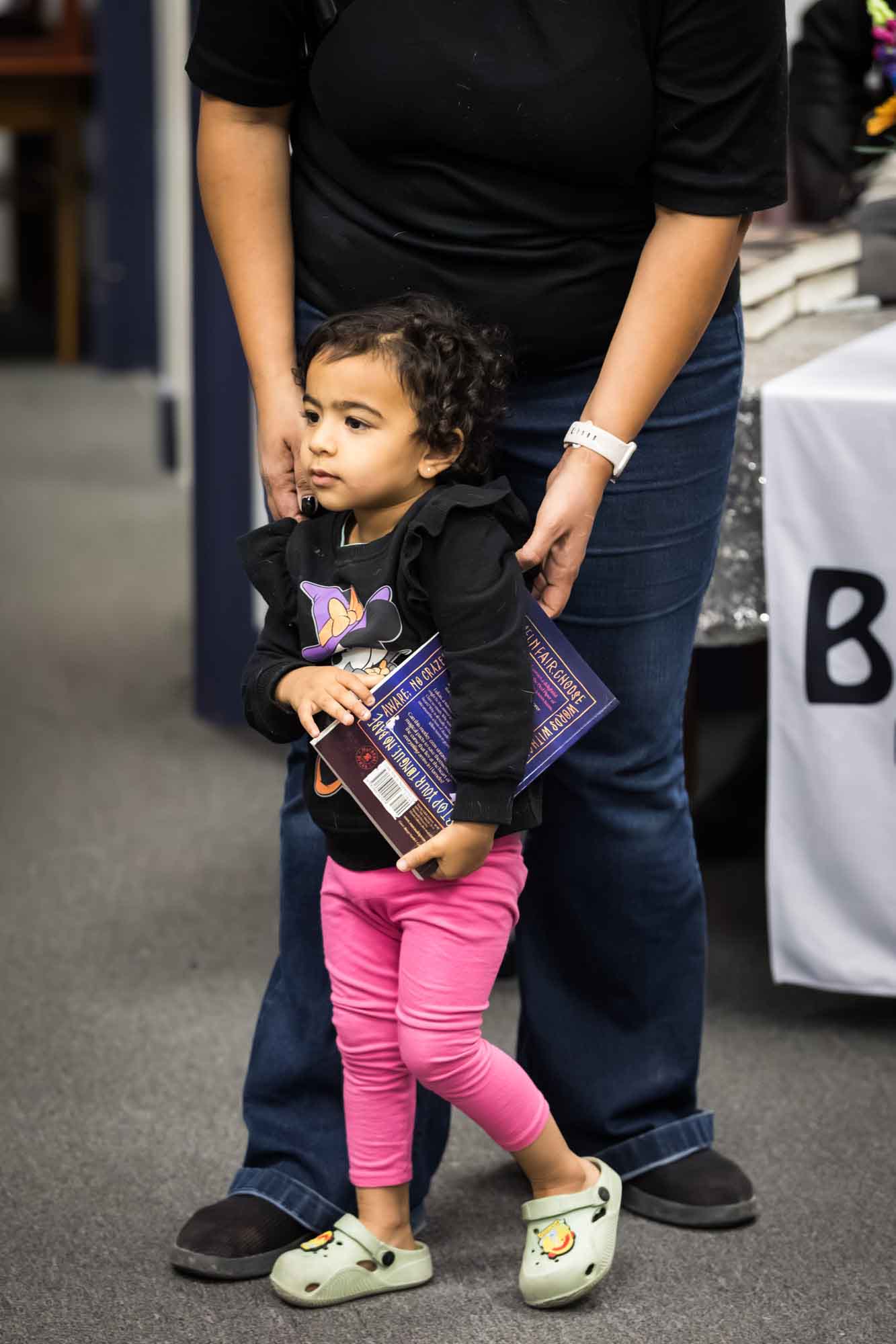 Austin book launch party photos of little girl holding Hameln book in front of woman with her hands on little girl's shoulders