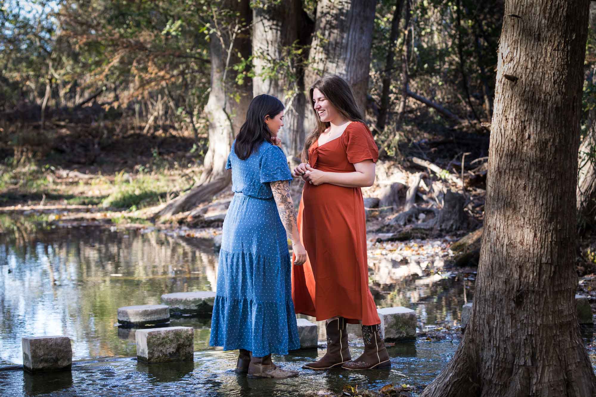 Cibolo Nature Center surprise proposal photos of woman in orange dress standing in front of woman in blue dress in the forest