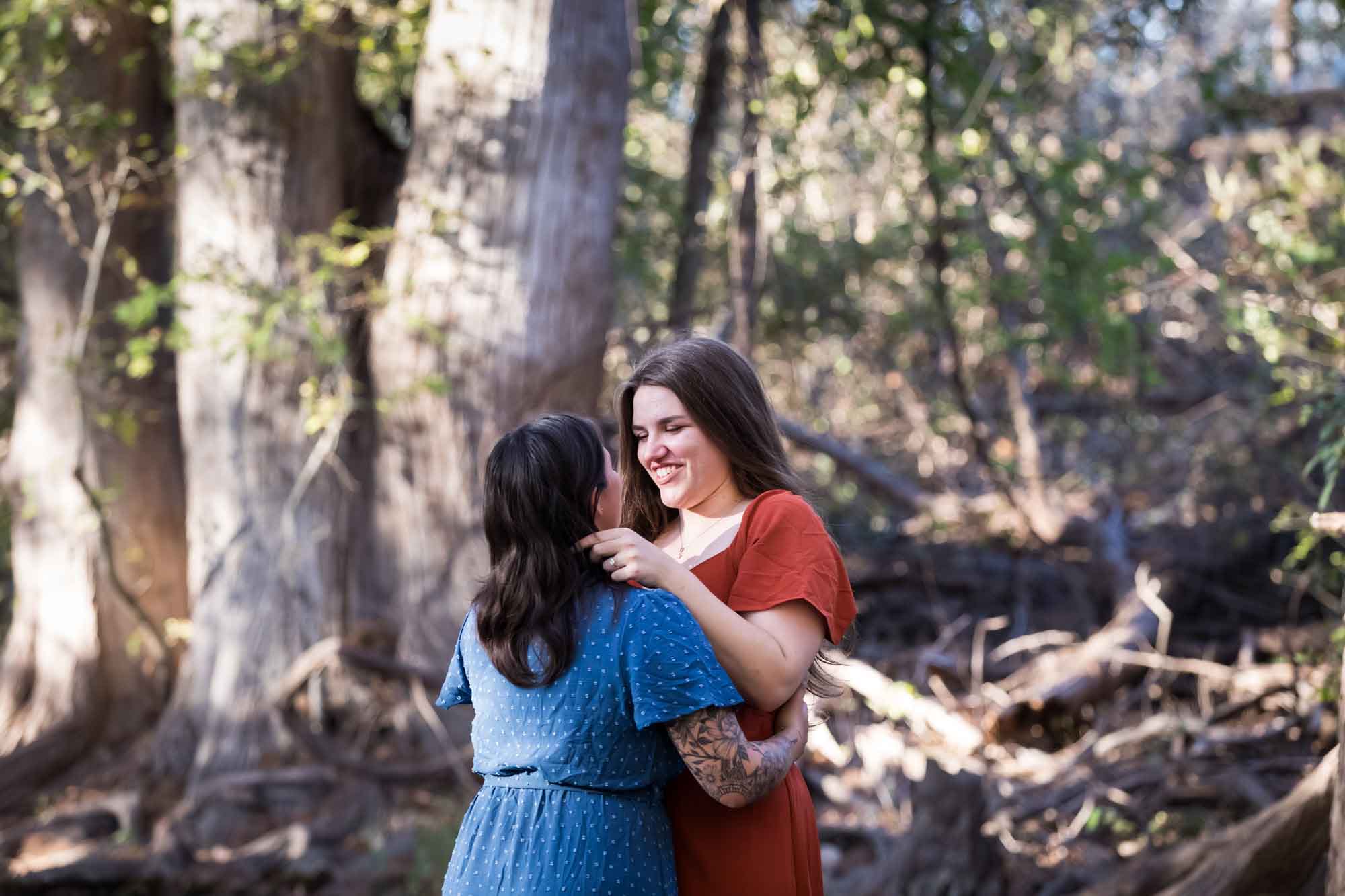 Cibolo Nature Center surprise proposal photos of woman in orange dress hugging woman in blue dress in the forest