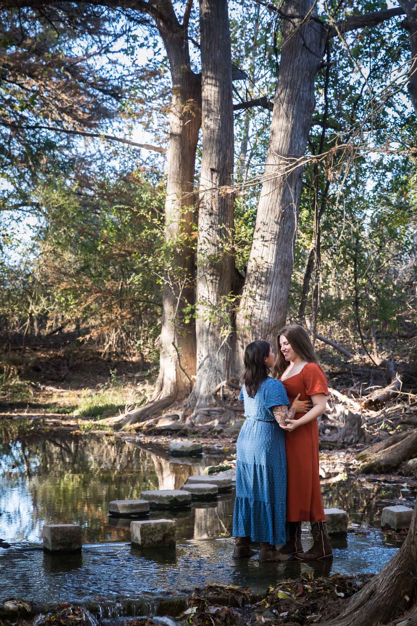 Cibolo Nature Center surprise proposal photos of woman in orange dress hugging woman in blue dress in the forest