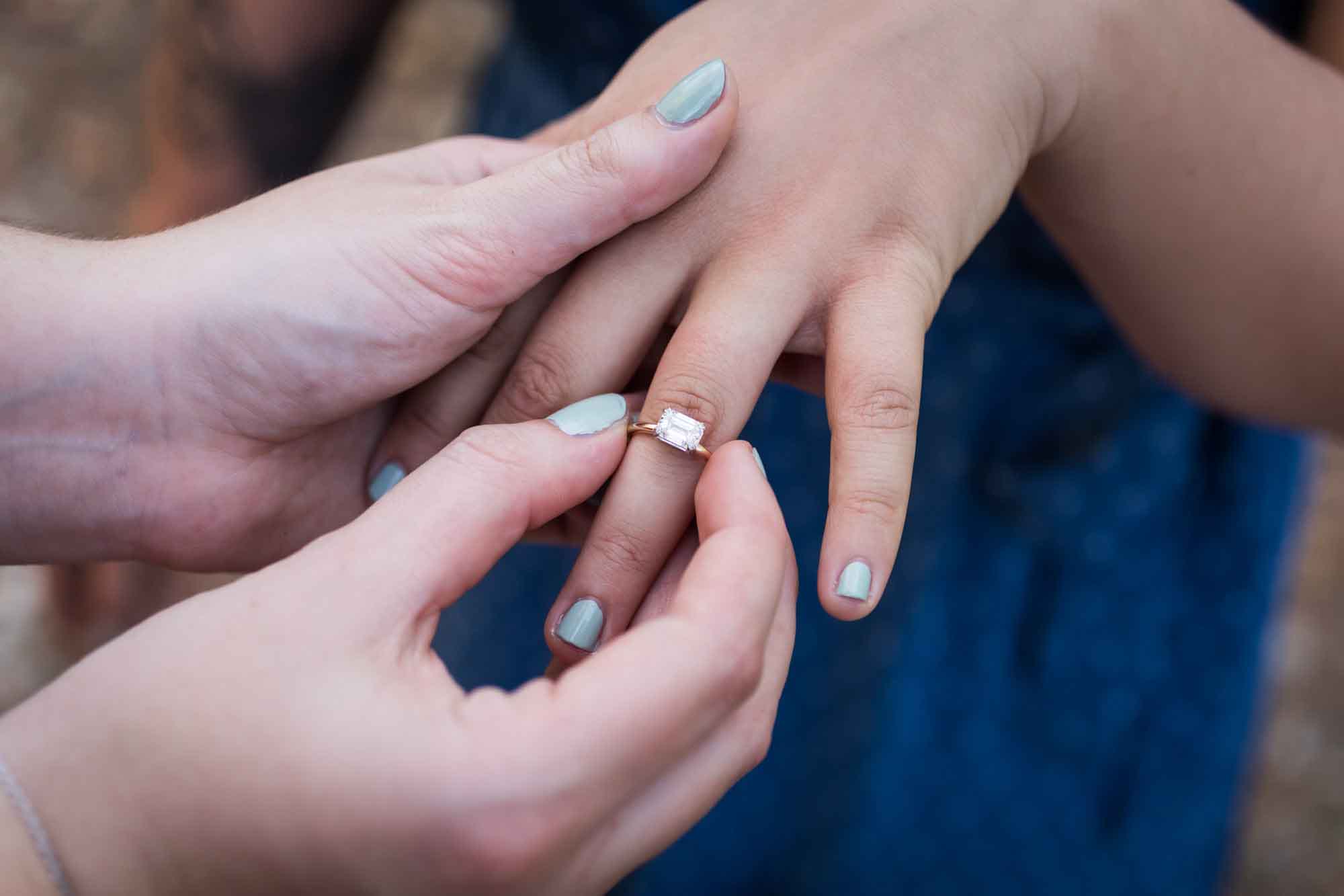 Close up on woman putting engagement ring on hand of another woman