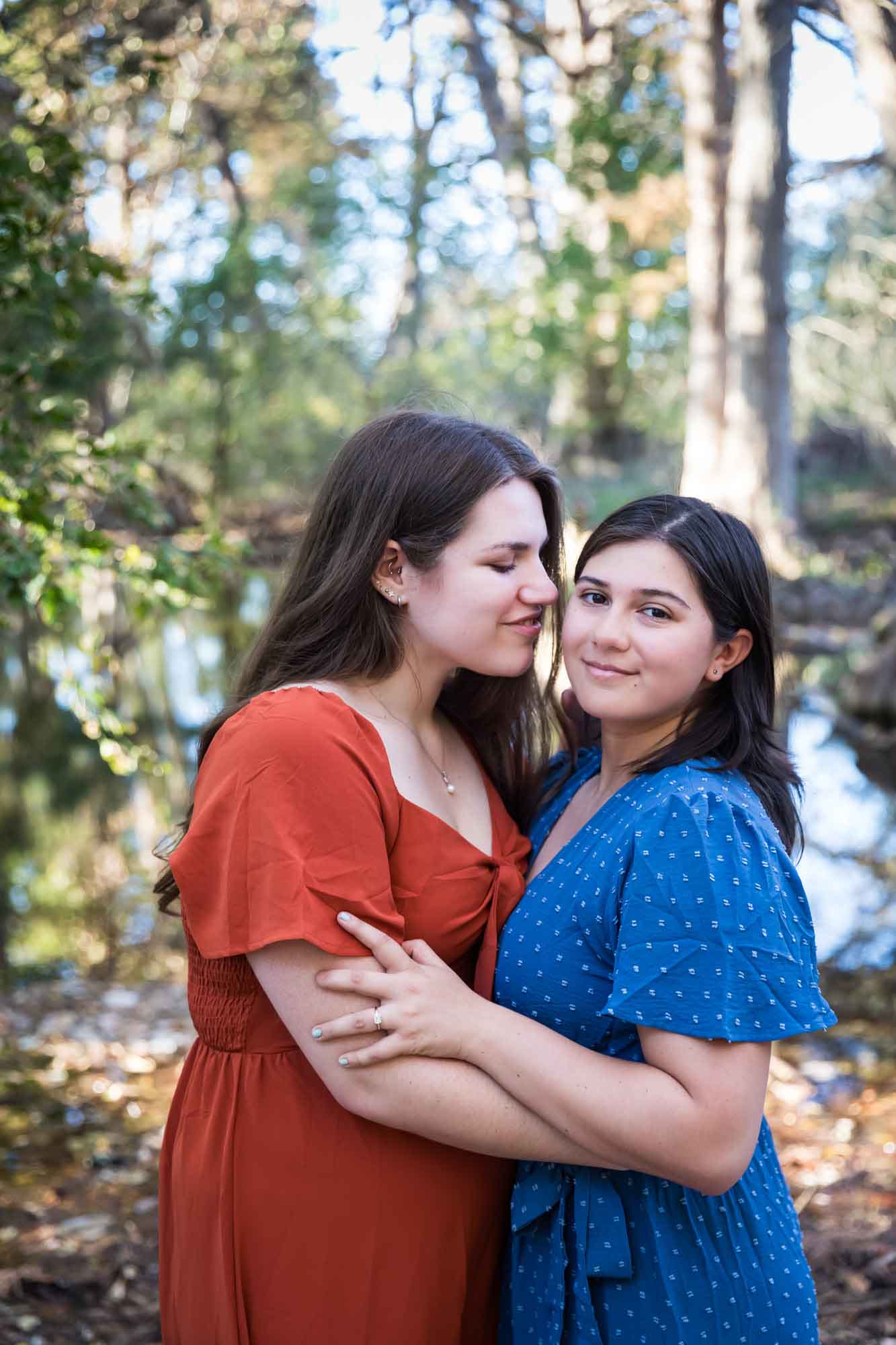 Cibolo Nature Center surprise proposal photos of woman in orange dress hugging woman in blue dress in the forest