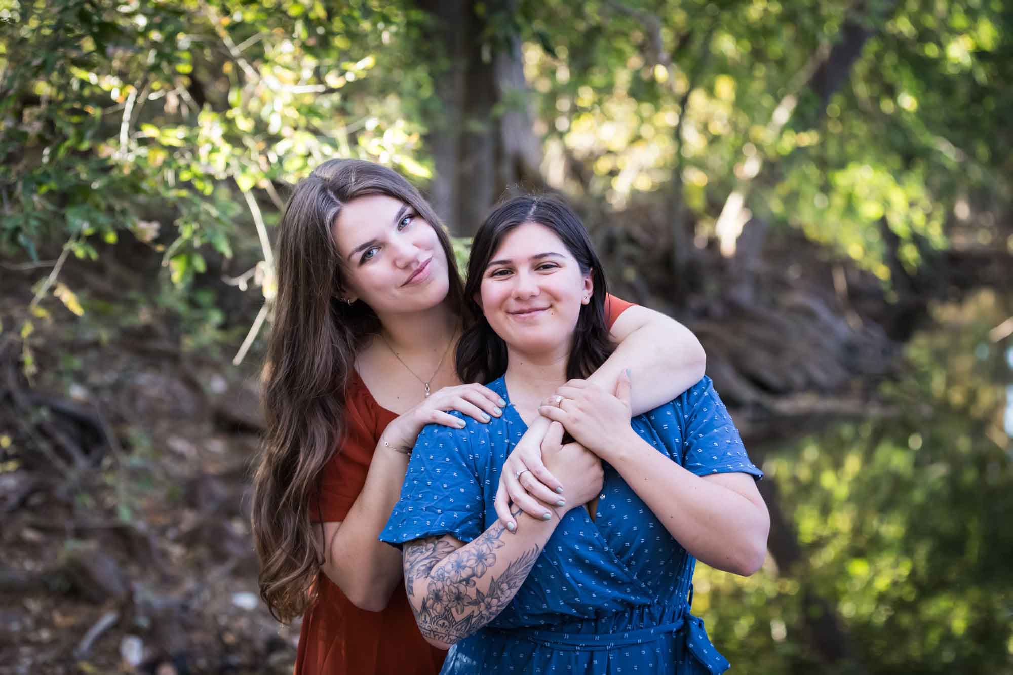 Cibolo Nature Center surprise proposal photos of woman in orange dress hugging woman in blue dress in the forest