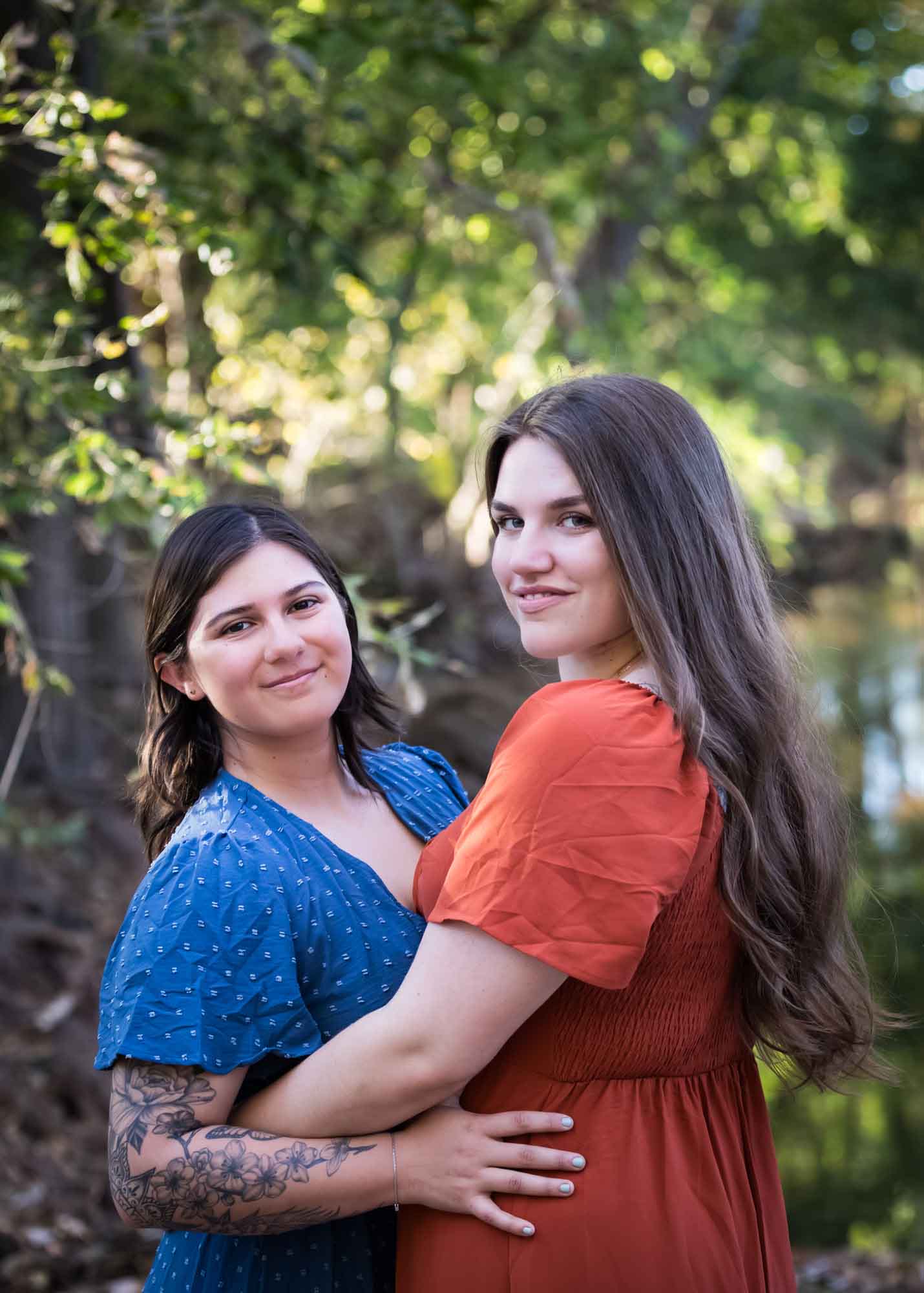 Cibolo Nature Center surprise proposal photos of woman in orange dress hugging woman in blue dress in the forest