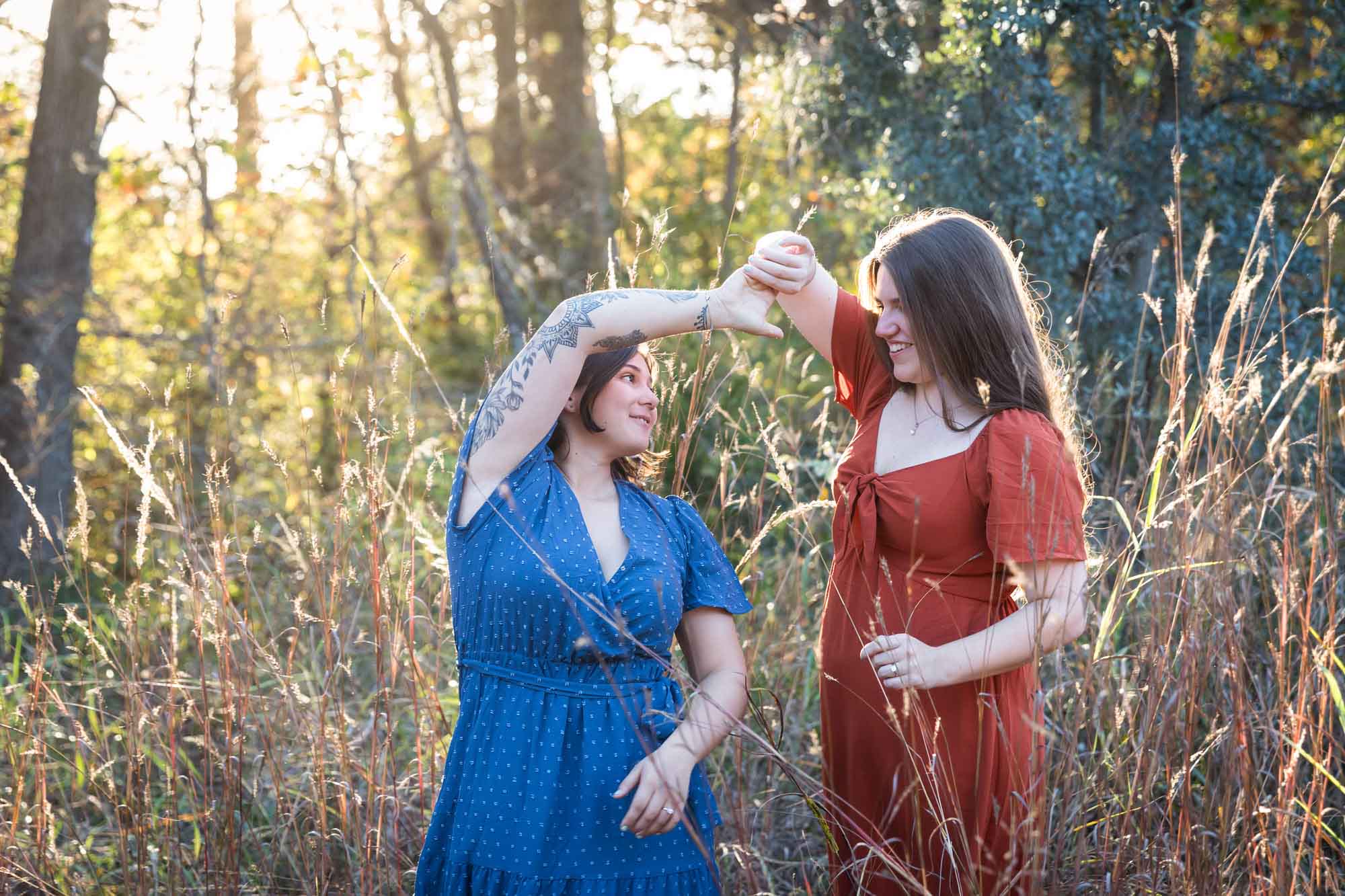 Cibolo Nature Center surprise proposal photos of woman in orange dress dancing with woman in blue dress in the forest