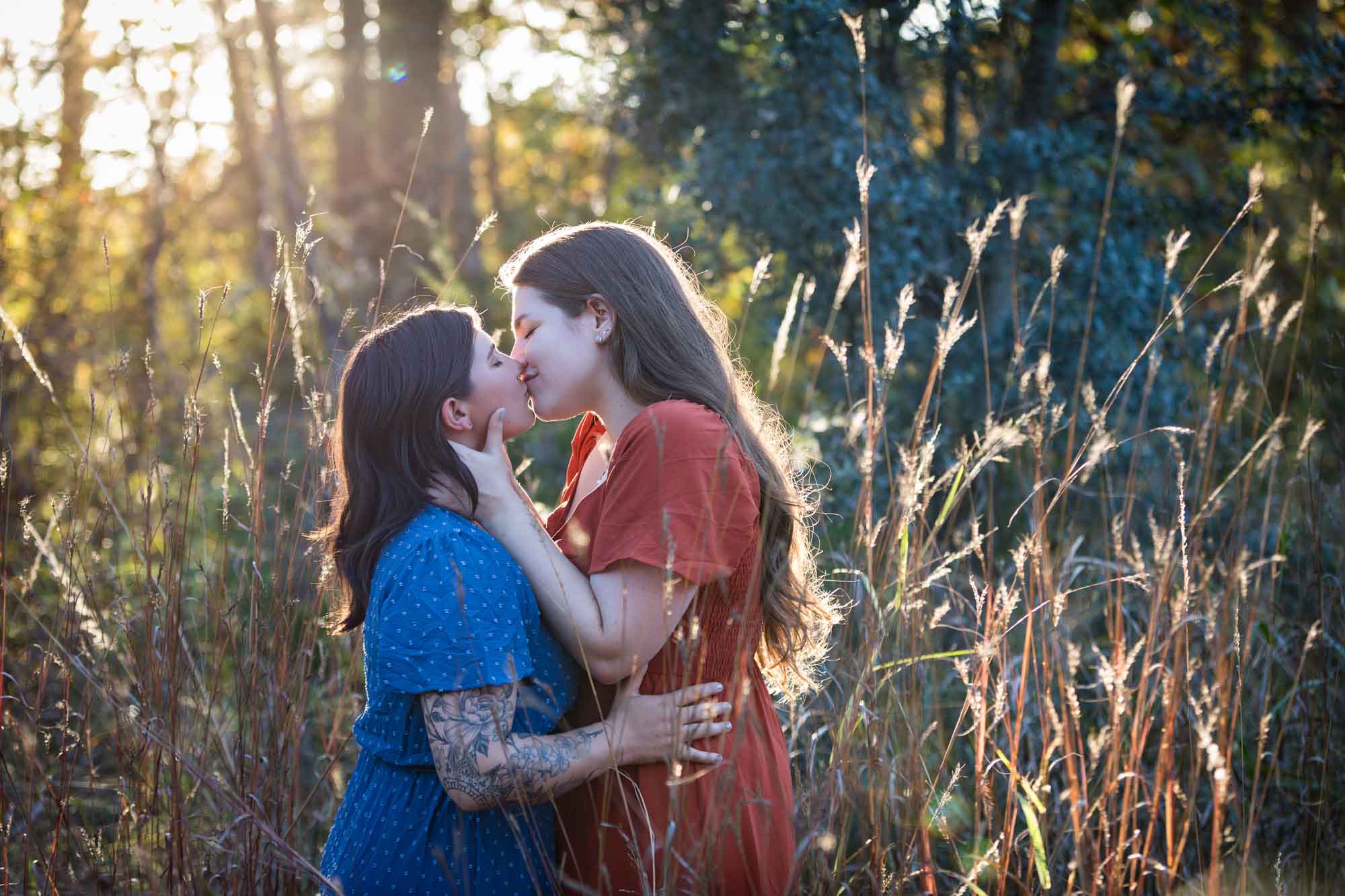 Cibolo Nature Center surprise proposal photos of woman in orange dress kissing woman in blue dress in the forest