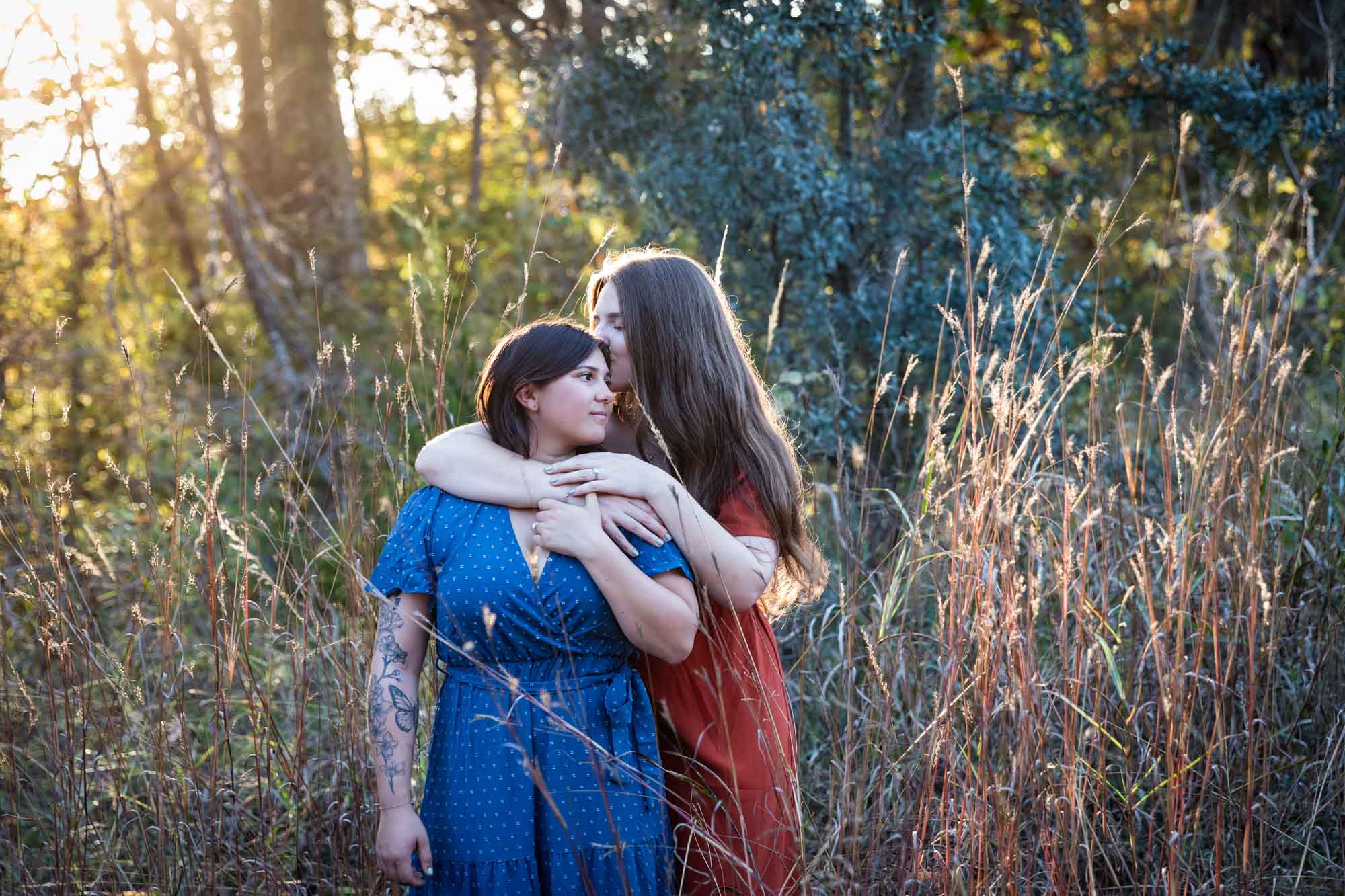 Cibolo Nature Center surprise proposal photos of woman in orange dress kissing woman in blue dress in the forest