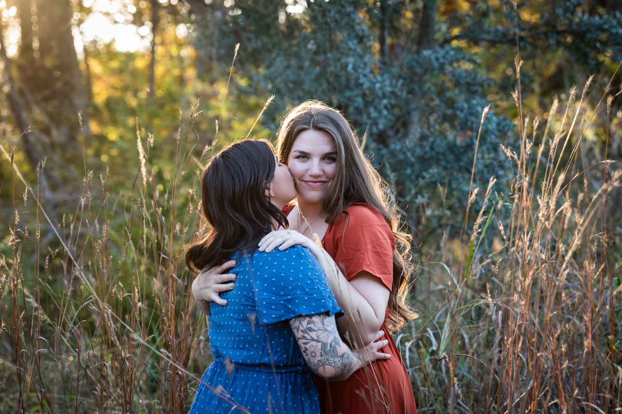 Cibolo Nature Center surprise proposal photos of woman in orange dress kissing woman in blue dress in the forest