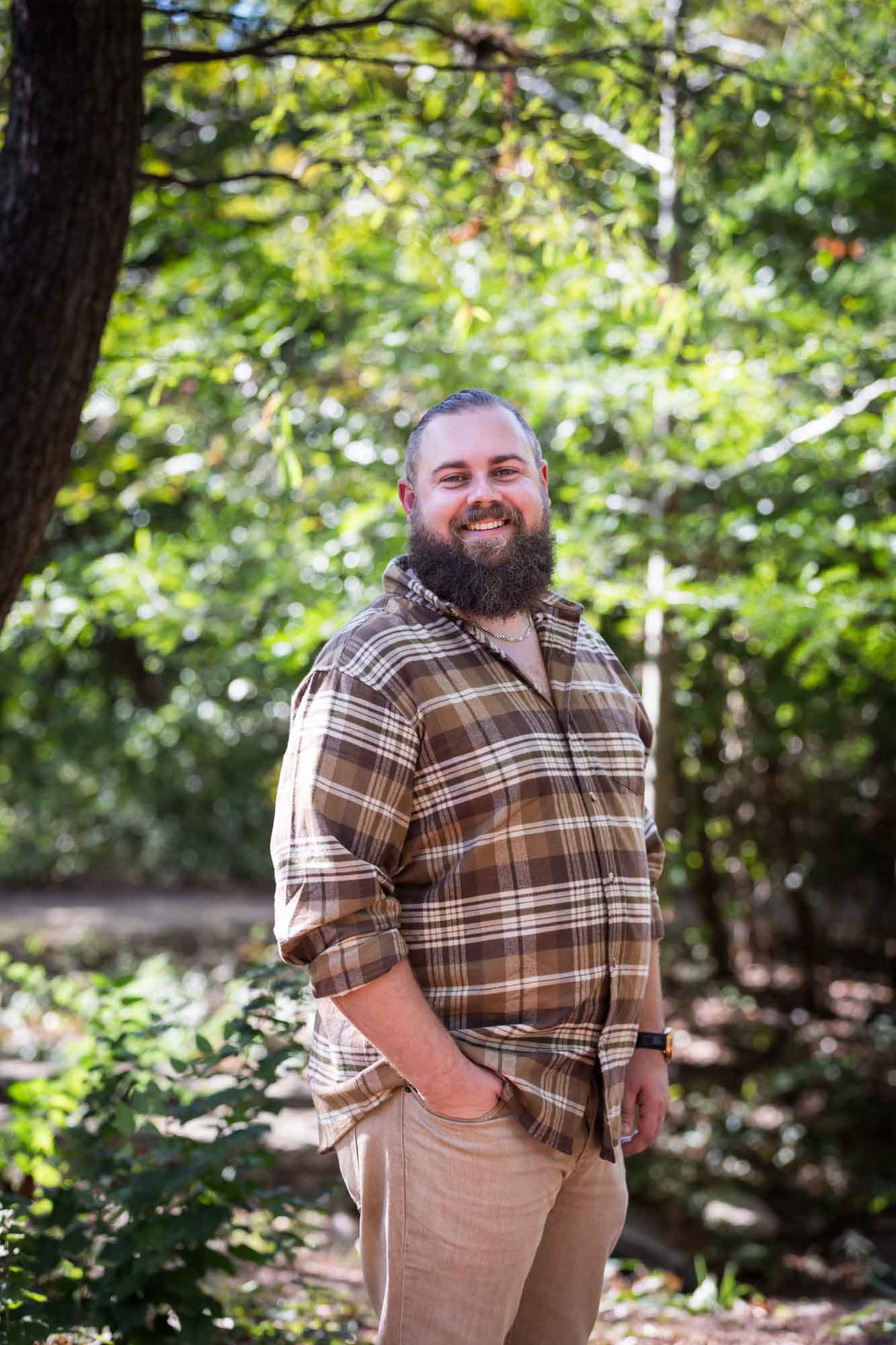 San Antonio Botanical Gardens family portrait of man with beard wearing brown plaid shirt standing in front of trees