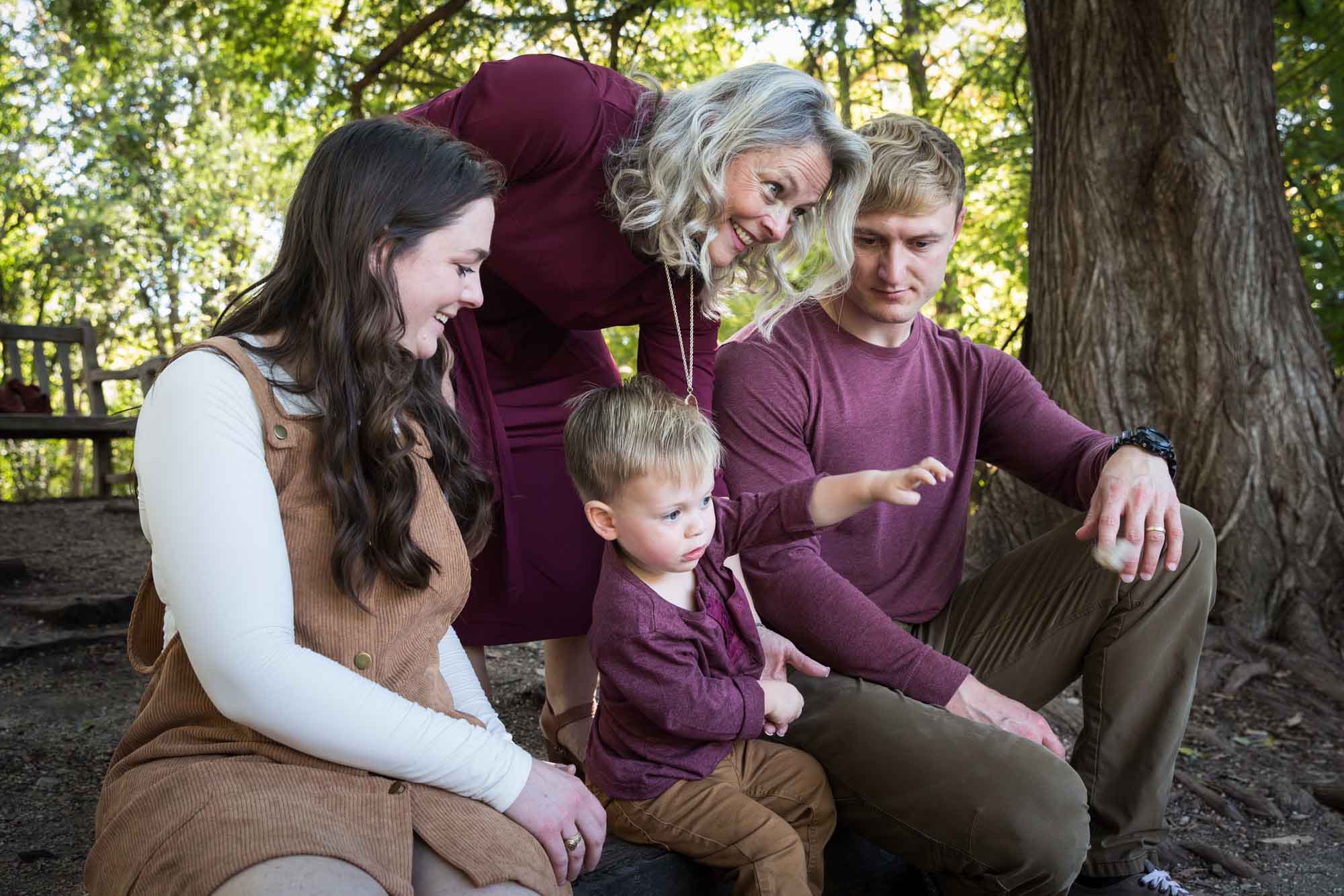 San Antonio Botanical Gardens family portrait of mother, father, and grandmother watching little boy throw something in the forest