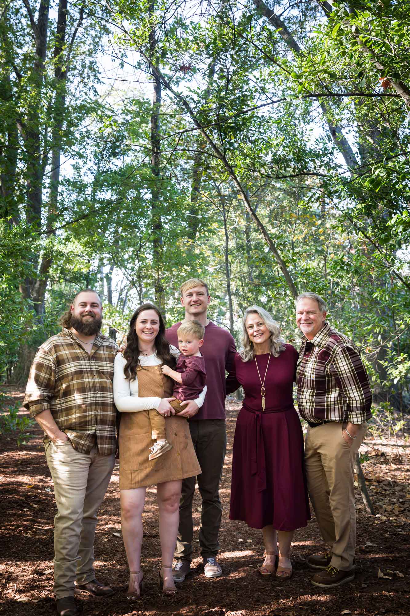 San Antonio Botanical Gardens family portrait of family consisting of grandparents, mother holding little boy, father, and adult man standing in the forest