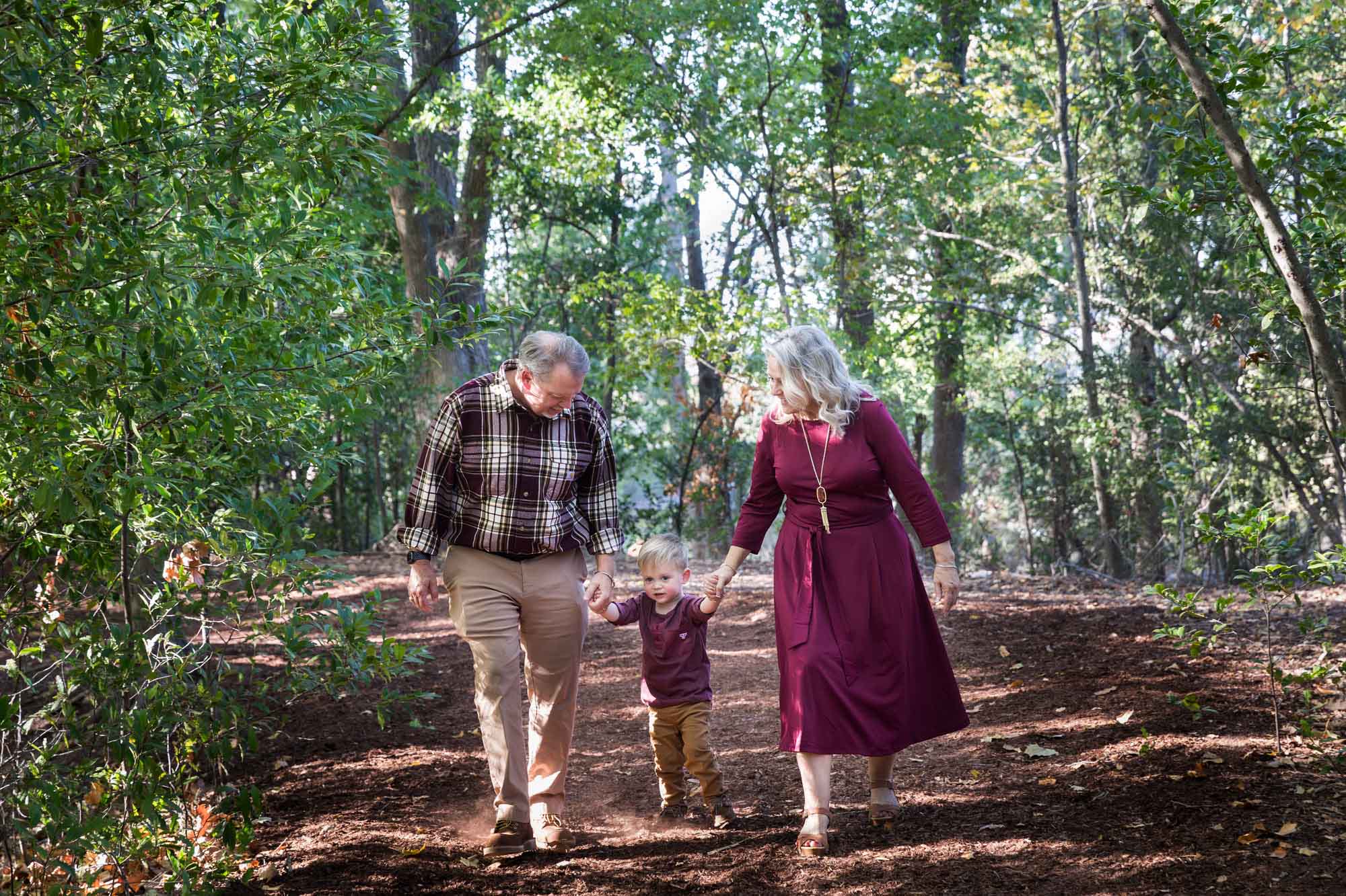 San Antonio Botanical Gardens family portrait of grandparents holding hands of little boy walking through the forest