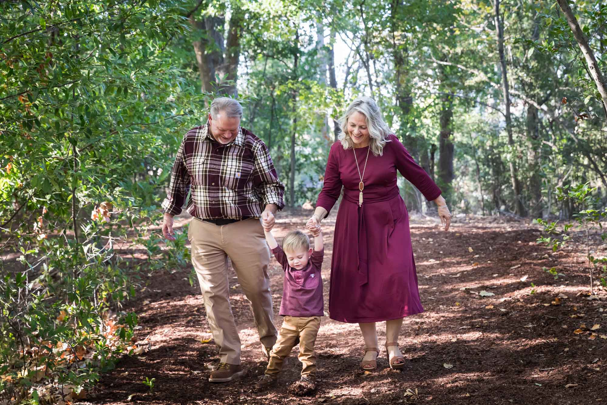 San Antonio Botanical Gardens family portrait of grandparents holding hands of little boy walking through the forest