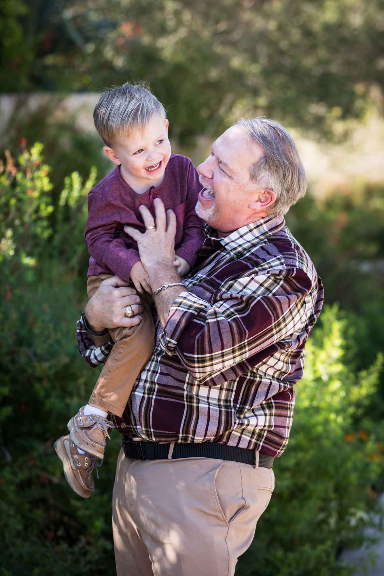 San Antonio Botanical Gardens family portrait of grandfather wearing plaid shirt and khaki pants playing with little boy wearing purple shirt and tan pants