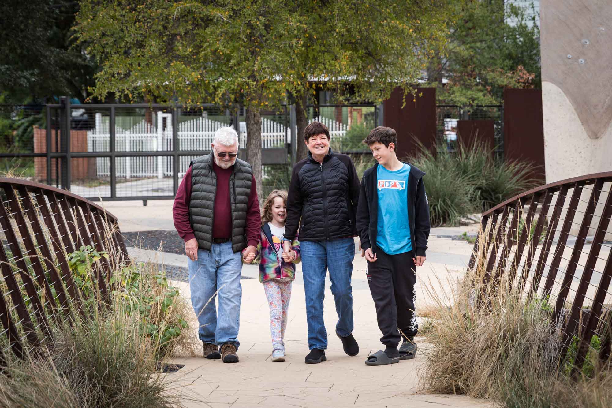Grandparents walking with little girl and older boy over a landscaped bridge during a Confluence Park family portrait session