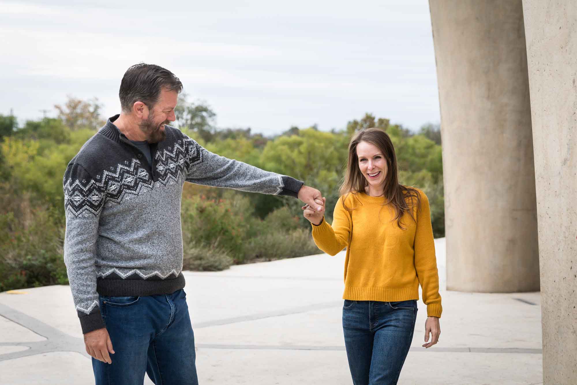 Man wearing grey sweater dancing with woman wearing yellow sweater and jeans during a Confluence Park family portrait session