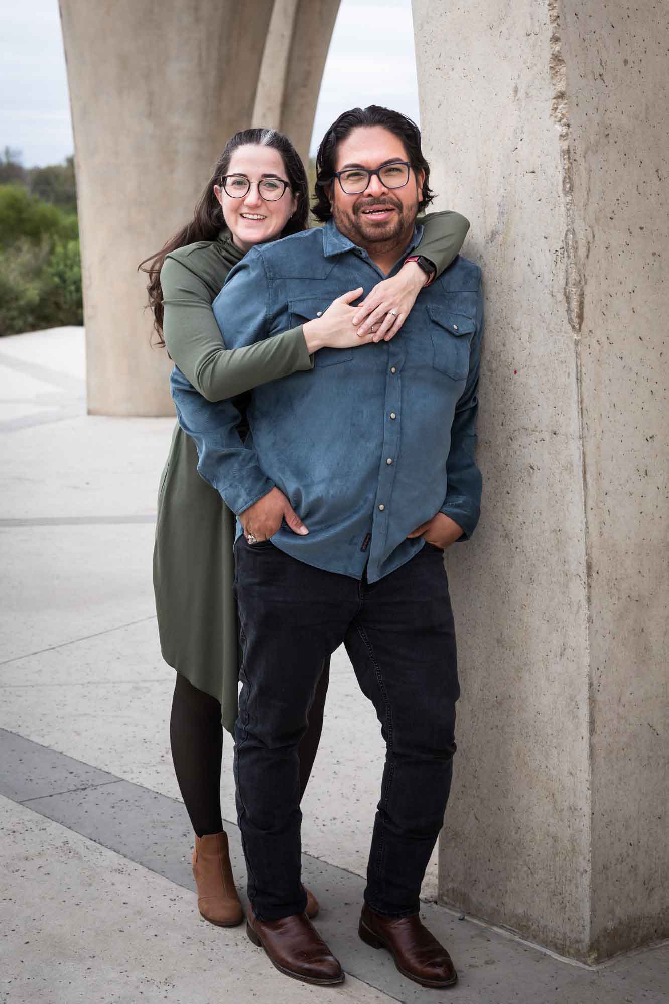 Man wearing denim long-sleeved shirt being hugged by a woman wearing green long-sleeved shirt during a Confluence Park family portrait session