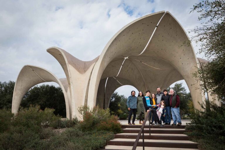 Family of eight people standing together on stairs under concrete arch during a Confluence Park family portrait session