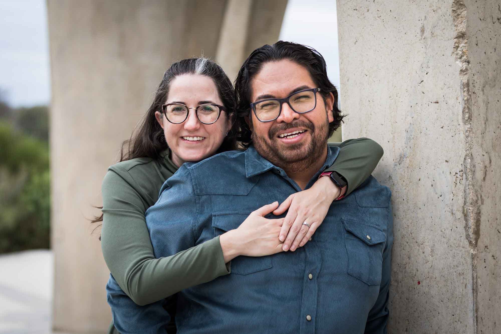 Man wearing denim long-sleeved shirt being hugged by a woman wearing green long-sleeved shirt during a Confluence Park family portrait session