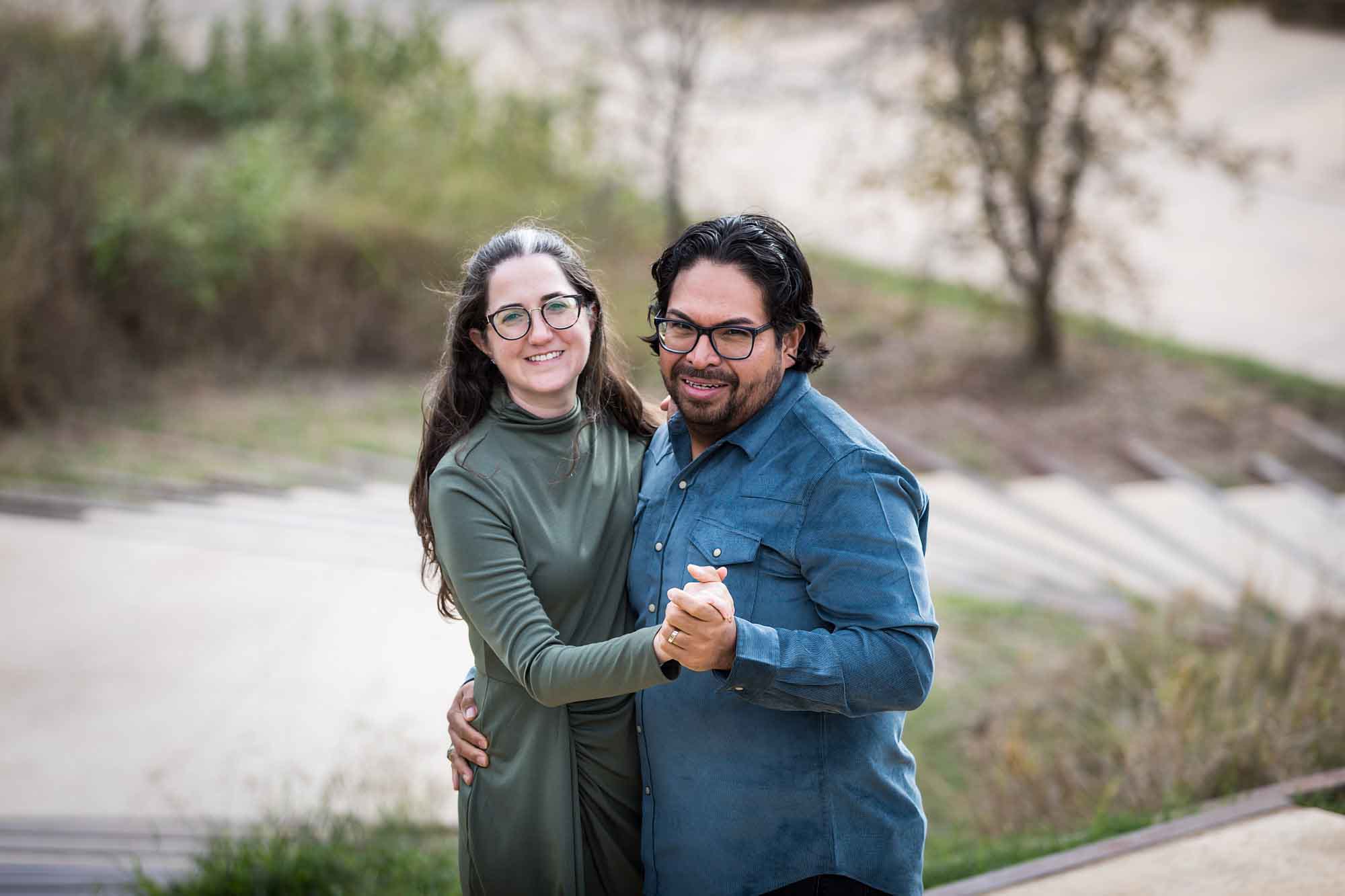 Man wearing denim long-sleeved shirt being dancing with a woman wearing green long-sleeved dress during a Confluence Park family portrait session