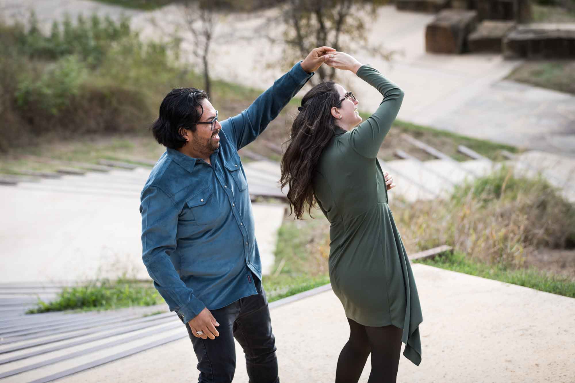 Man wearing denim long-sleeved shirt being dancing with a woman wearing green long-sleeved dress during a Confluence Park family portrait session