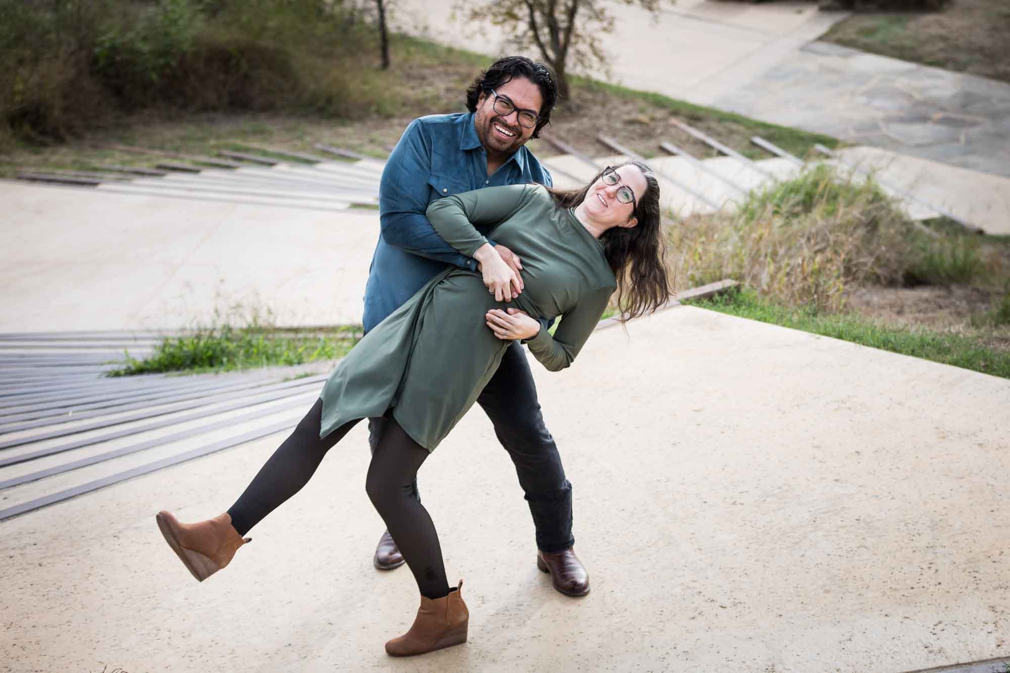 Man wearing denim long-sleeved shirt being dancing with a woman wearing green long-sleeved dress during a Confluence Park family portrait session