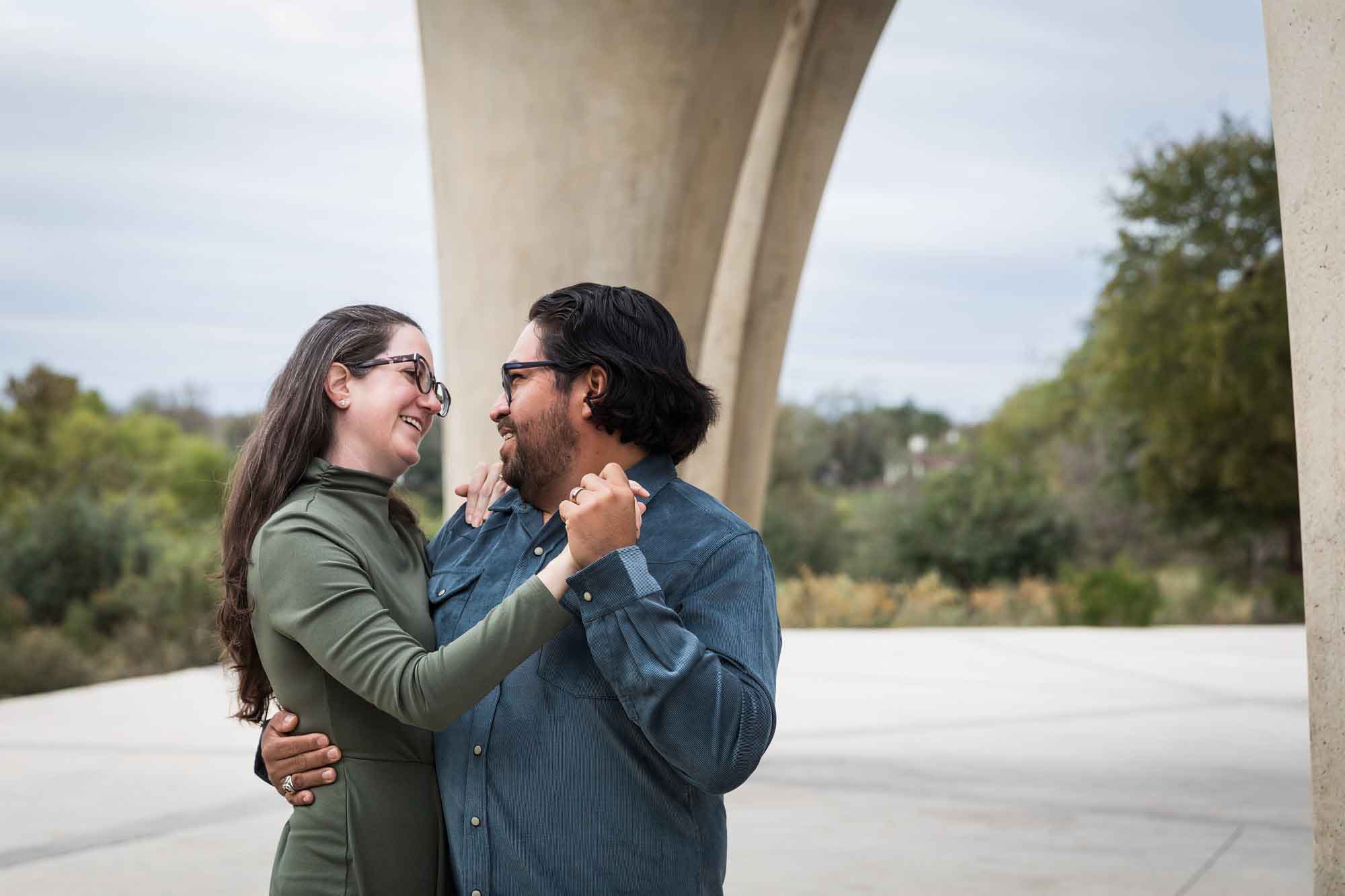 Man wearing denim long-sleeved shirt dancing with woman wearing green dress during a Confluence Park family portrait session