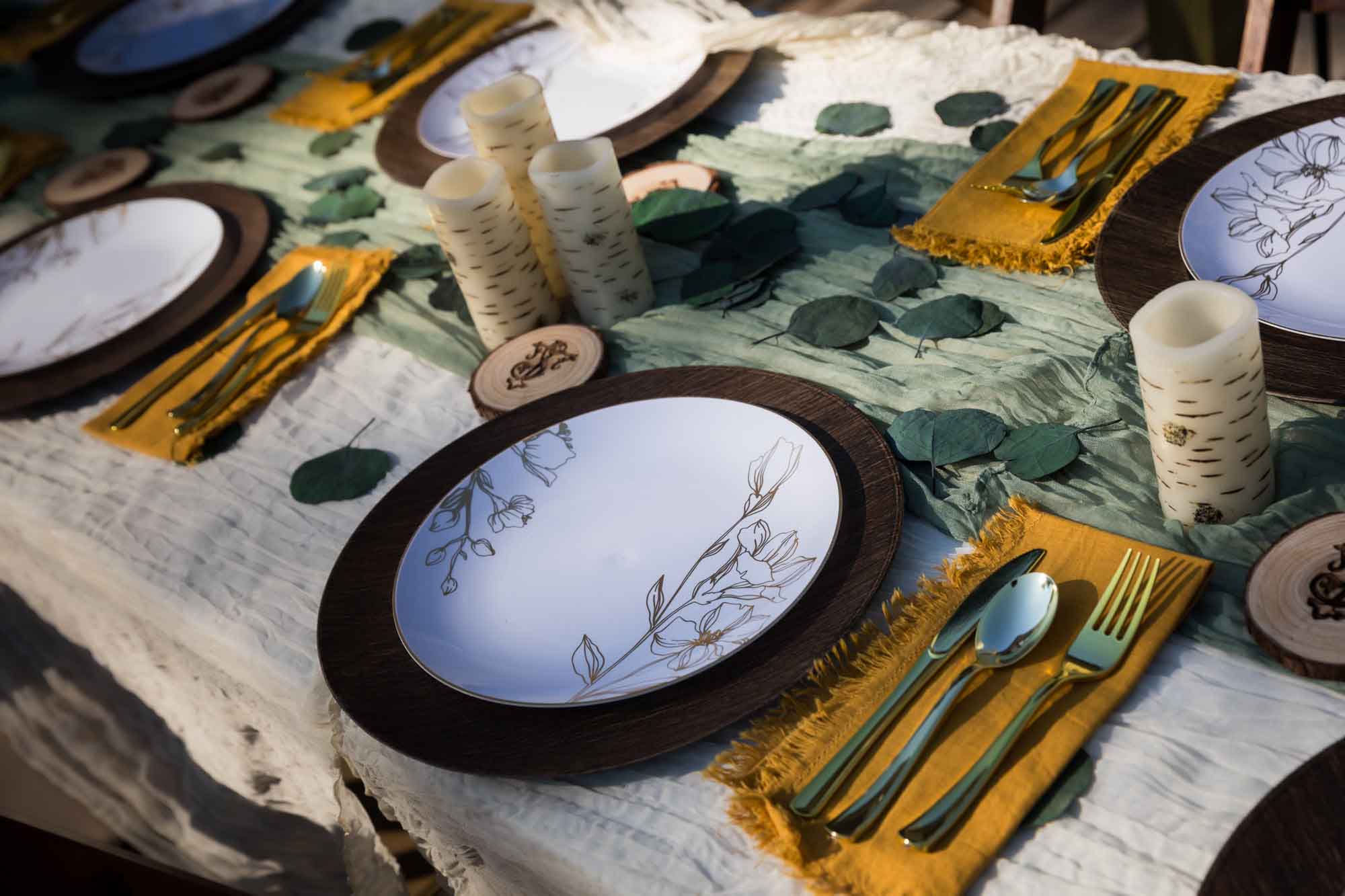 Table with green runner, plastic plates, candles, and wooden coasters at a San Antonio DIY wedding