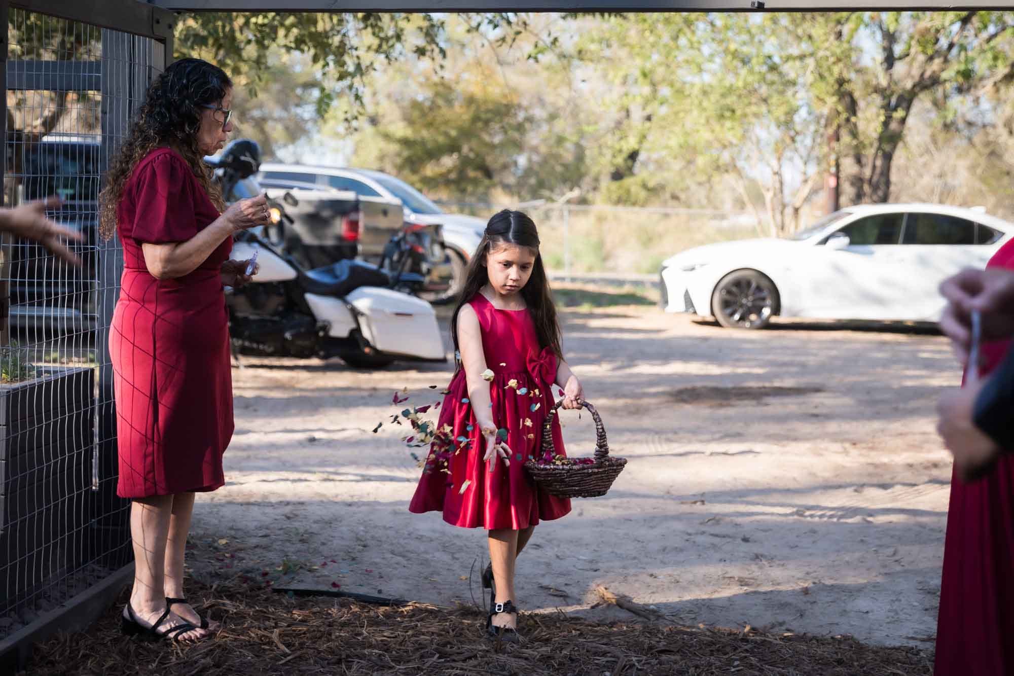 Flower girl wearing red dress putting down petals at a San Antonio DIY wedding